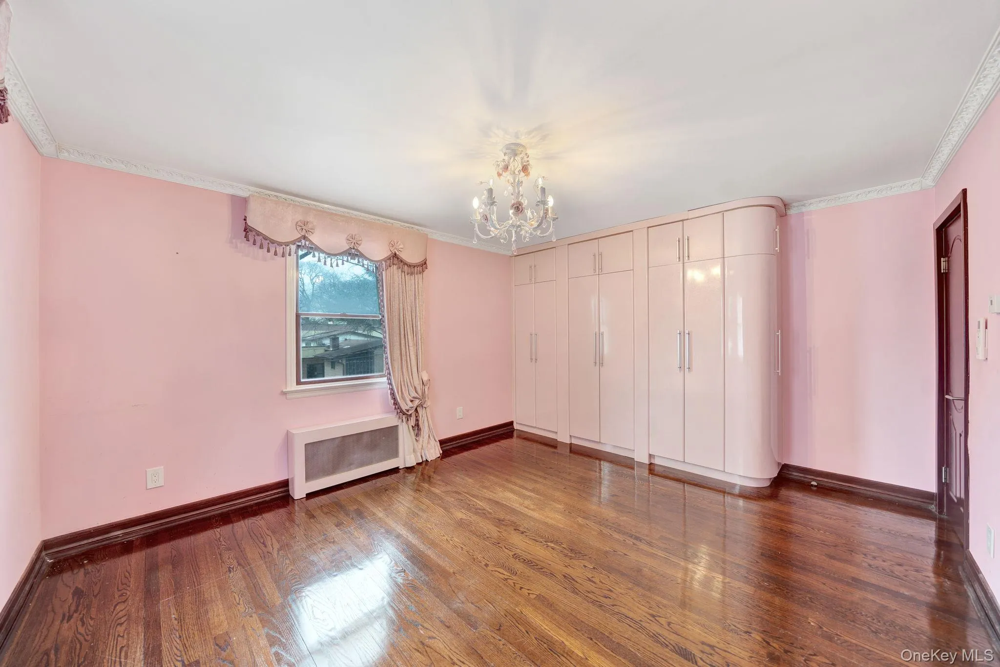 Unfurnished room featuring dark wood-style floors, radiator heating unit, a chandelier, and ornamental molding Unfurnished room featuring dark wood-style floors, radiator heating unit, a chandelier, and ornamental molding