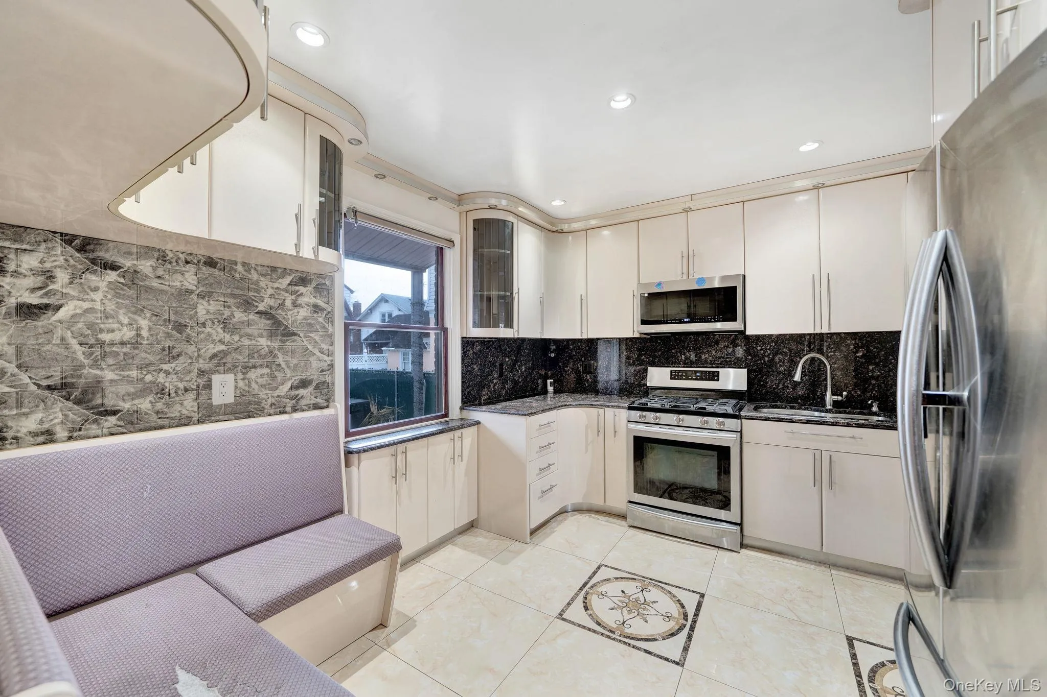 Kitchen featuring appliances with stainless steel finishes, glass insert cabinets, dark stone counters, recessed lighting, and light tile patterned floors Kitchen featuring appliances with stainless steel finishes, glass insert cabinets, dark stone counters, recessed lighting, and light tile patterned floors