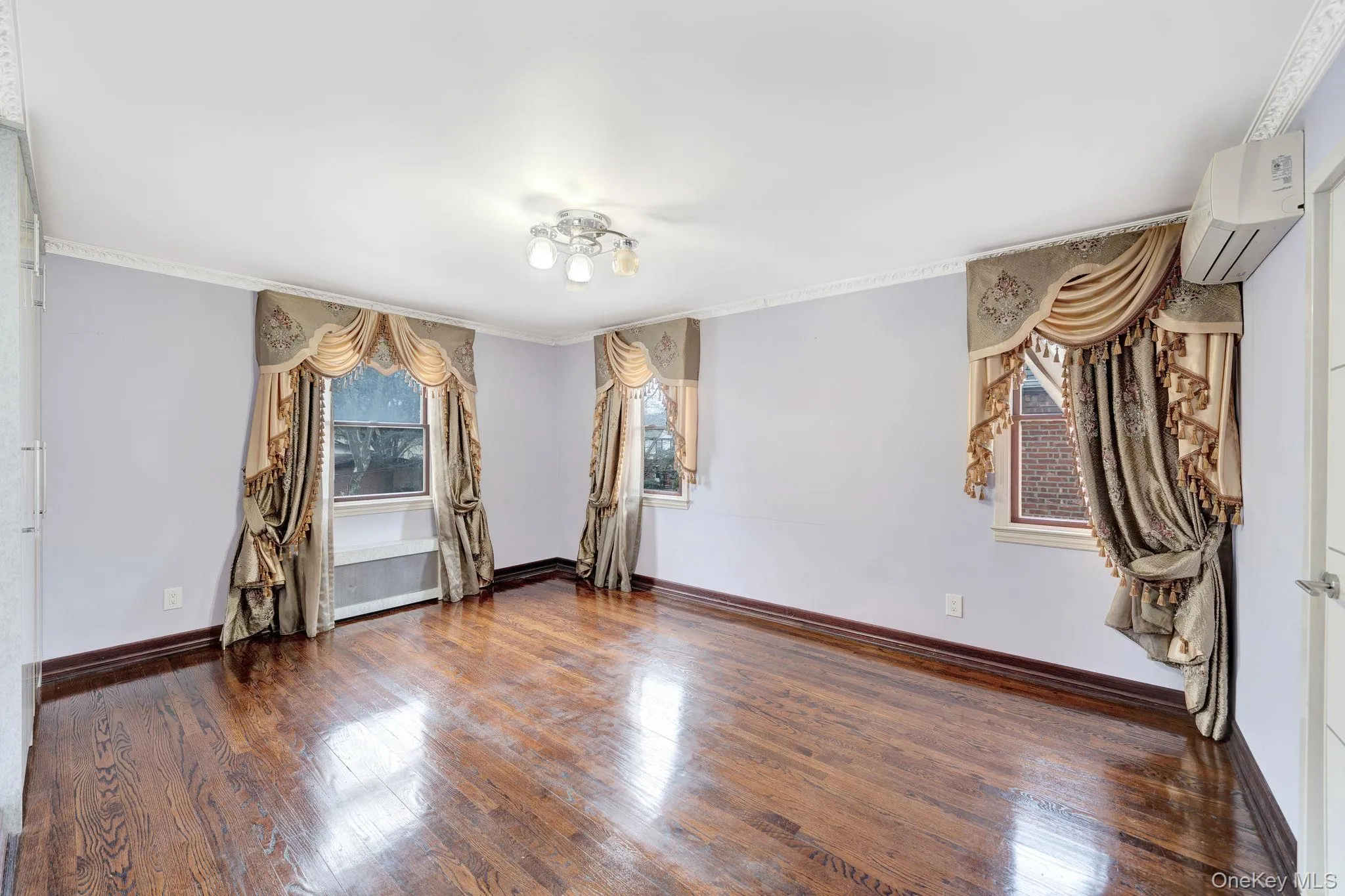 Spare room featuring dark wood finished floors, a wall unit AC, and ornamental molding Spare room featuring dark wood finished floors, a wall unit AC, and ornamental molding