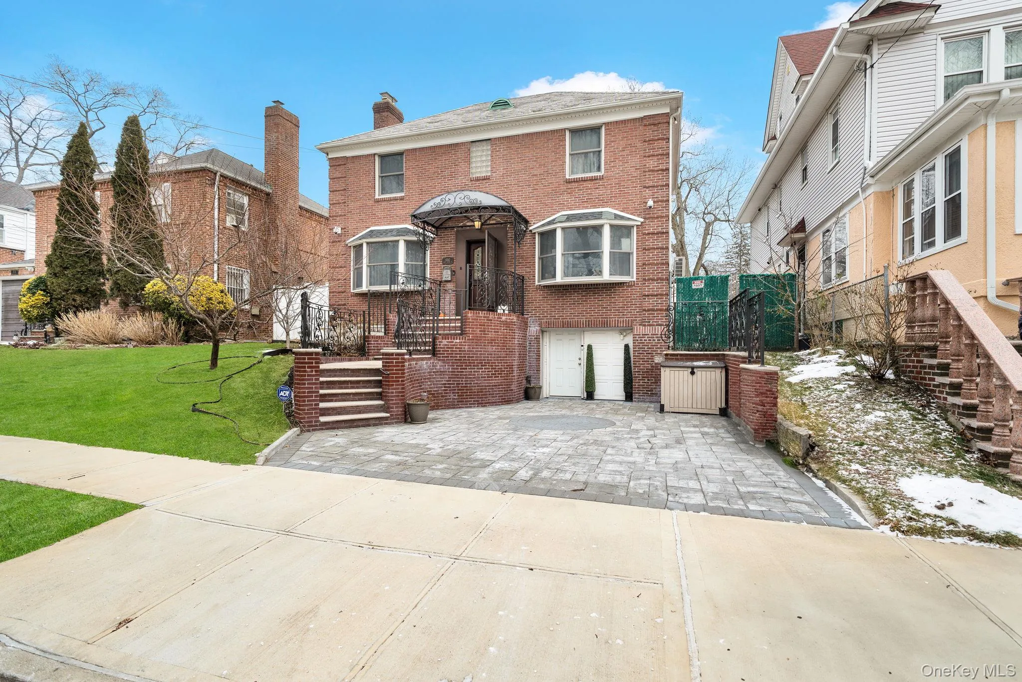 View of front facade featuring brick siding, a front lawn, an attached garage, driveway, and a chimney View of front facade featuring brick siding, a front lawn, an attached garage, driveway, and a chimney
