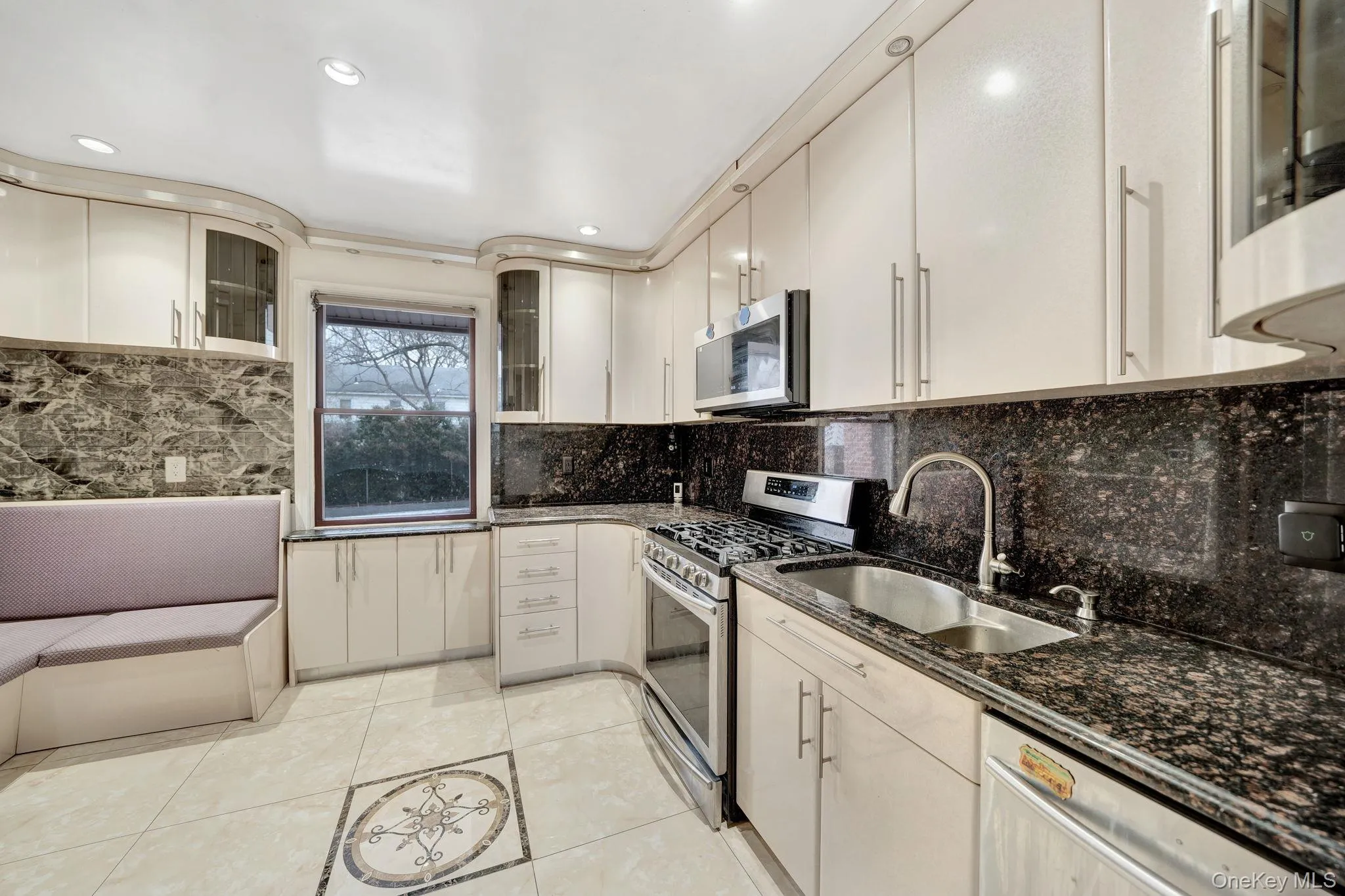 Kitchen featuring glass insert cabinets, stainless steel appliances, decorative backsplash, dark stone countertops, and recessed lighting Kitchen featuring glass insert cabinets, stainless steel appliances, decorative backsplash, dark stone countertops, and recessed lighting