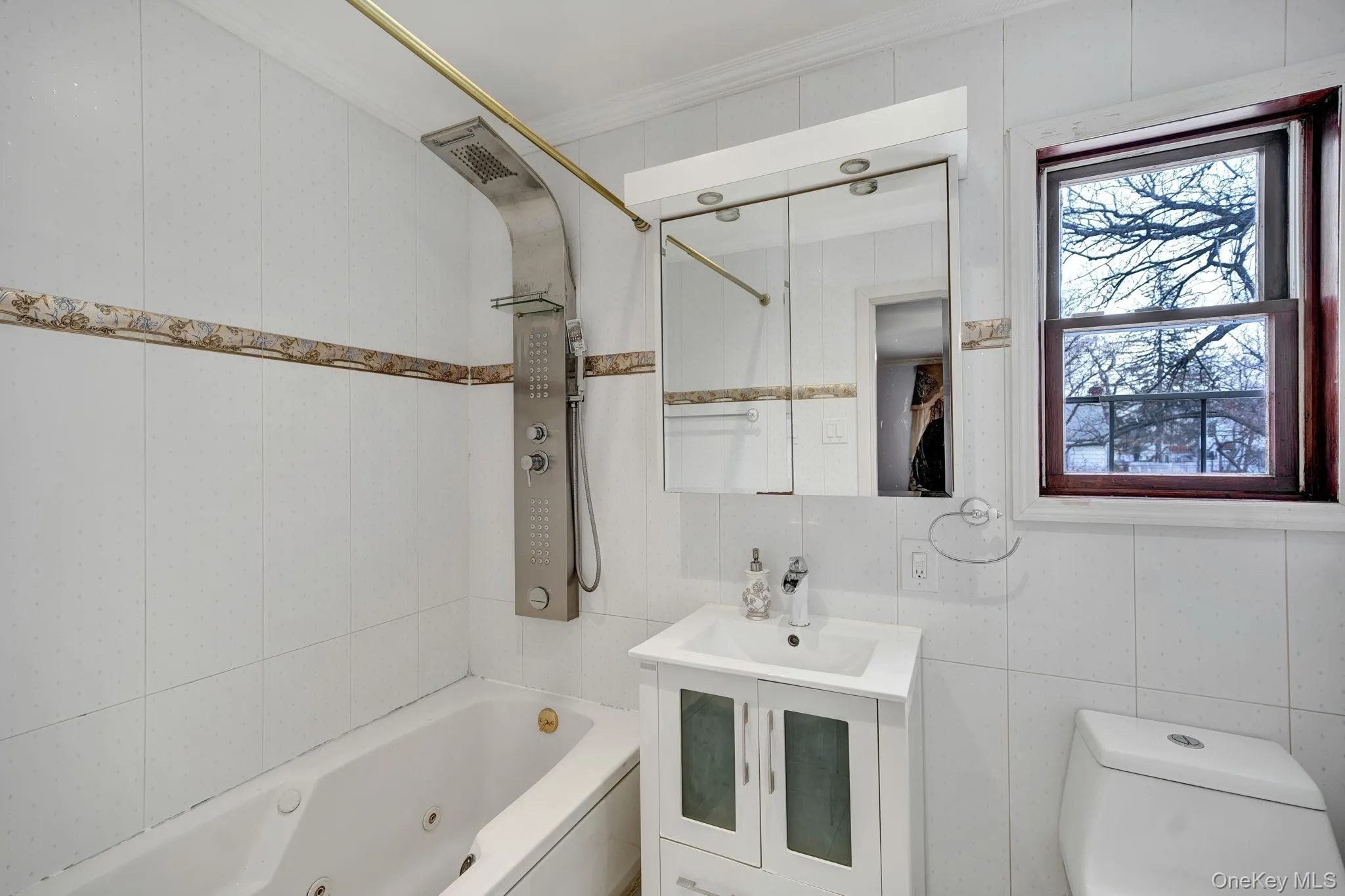 Bathroom with tile walls, a combined bath / shower with jetted tub, vanity, and ornamental molding Bathroom with tile walls, a combined bath / shower with jetted tub, vanity, and ornamental molding