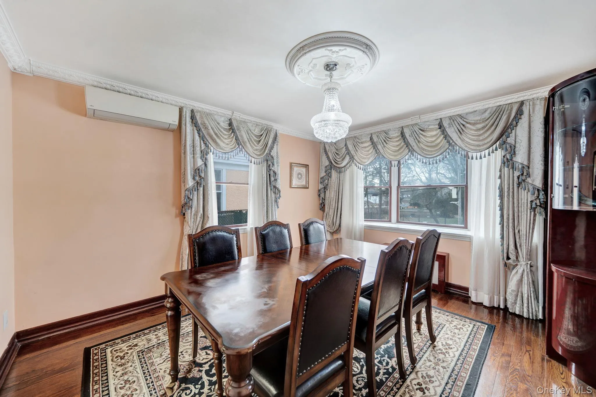 Dining area featuring a wall mounted AC, dark wood-type flooring, and crown molding Dining area featuring a wall mounted AC, dark wood-type flooring, and crown molding
