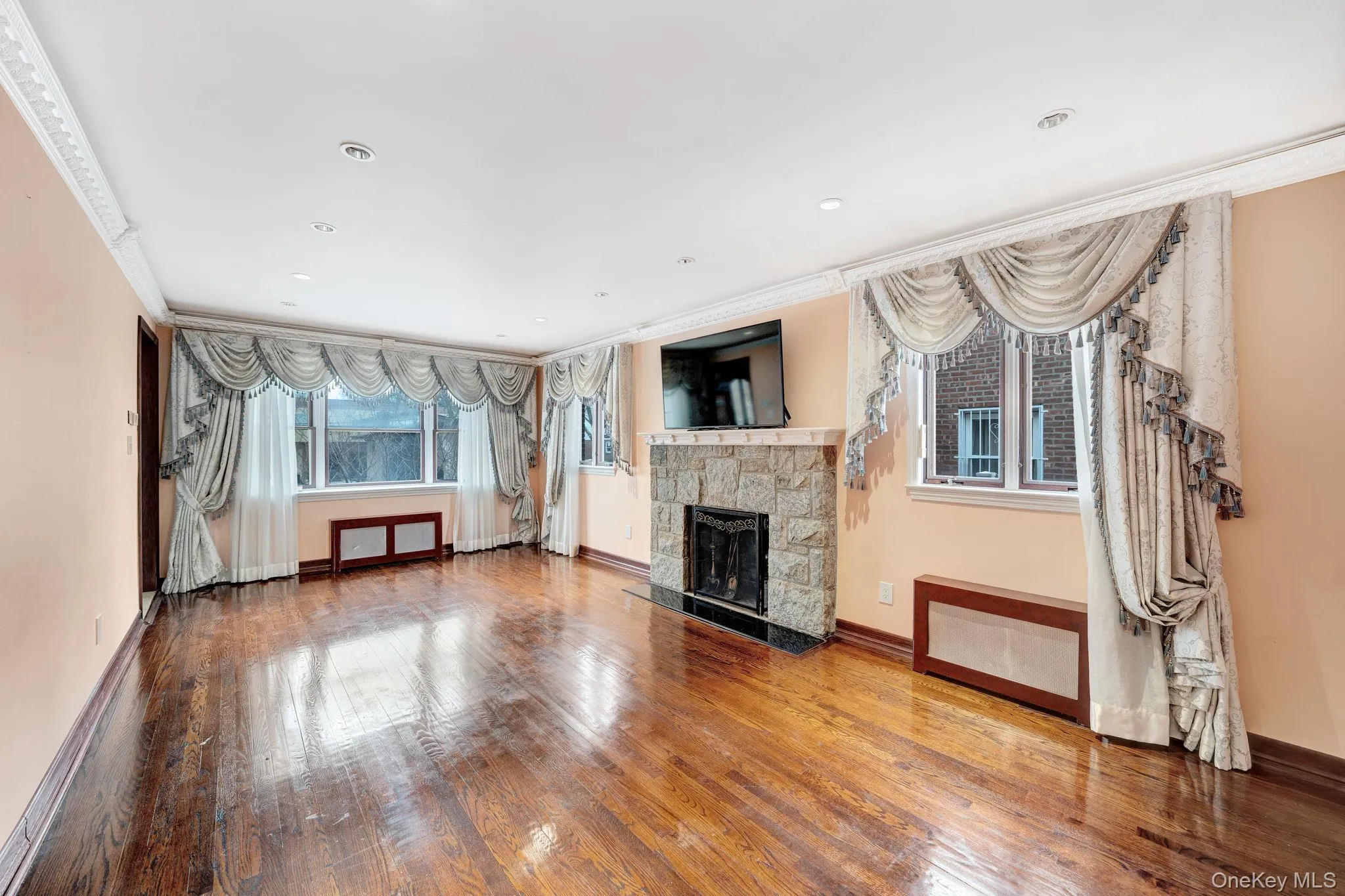 Unfurnished living room with a stone fireplace, wood-type flooring, recessed lighting, and crown molding Unfurnished living room with a stone fireplace, wood-type flooring, recessed lighting, and crown molding