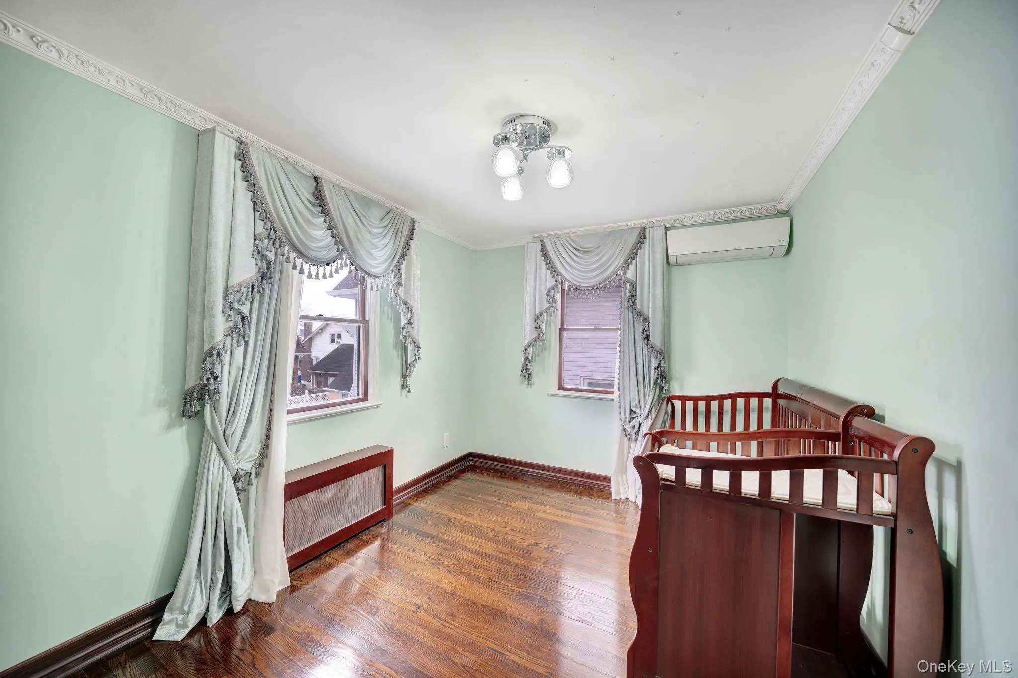 Bedroom with dark wood-type flooring, a wall mounted AC, and ornamental molding Bedroom with dark wood-type flooring, a wall mounted AC, and ornamental molding
