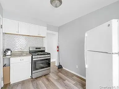 Kitchen with freestanding refrigerator, stainless steel gas range oven, white cabinets, and tasteful backsplash Kitchen with freestanding refrigerator, stainless steel gas range oven, white cabinets, and tasteful backsplash