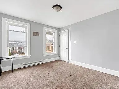Unfurnished room featuring carpet flooring and a baseboard radiator Unfurnished room featuring carpet flooring and a baseboard radiator