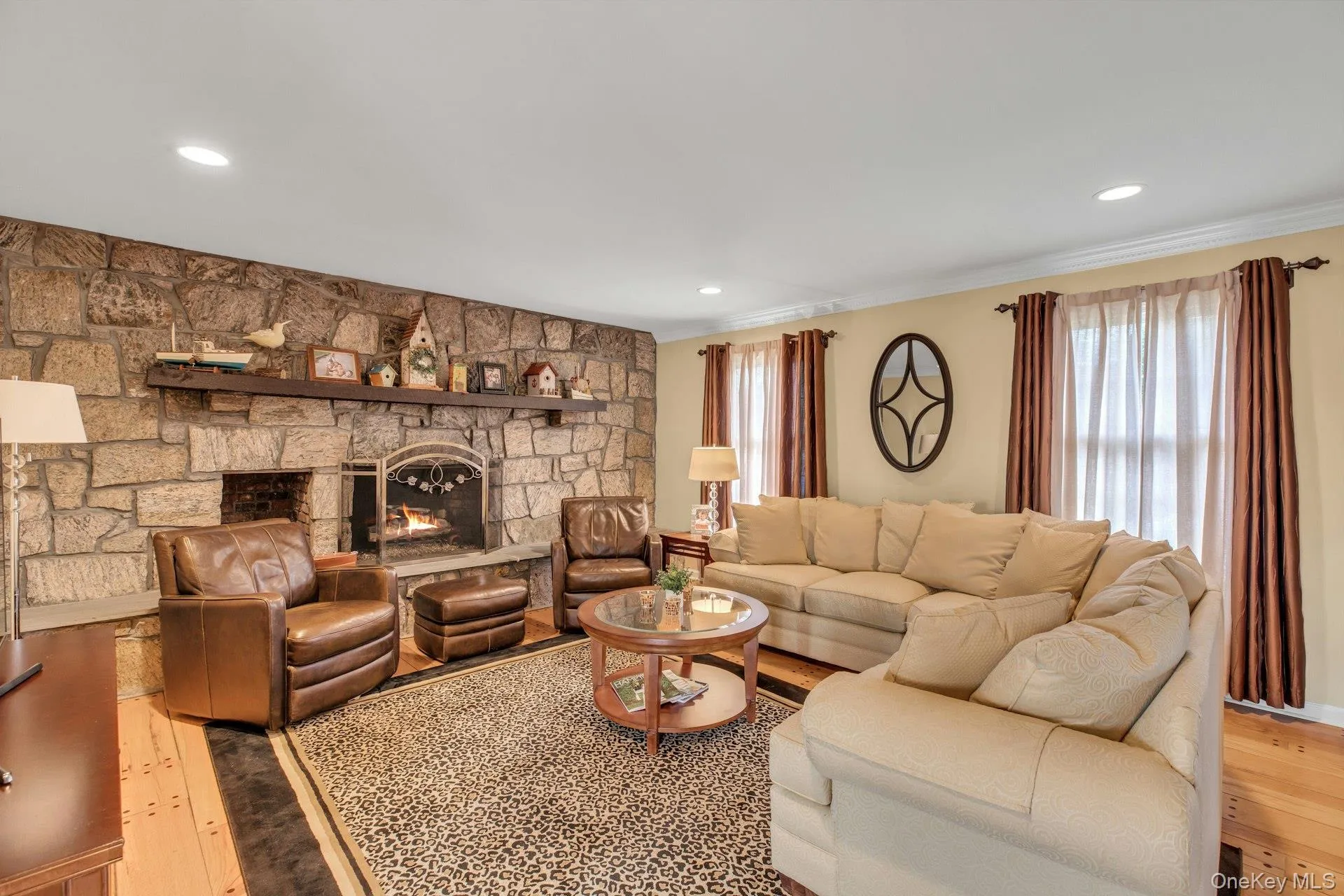 Living area with a fireplace, light wood-type flooring, recessed lighting, and ornamental molding