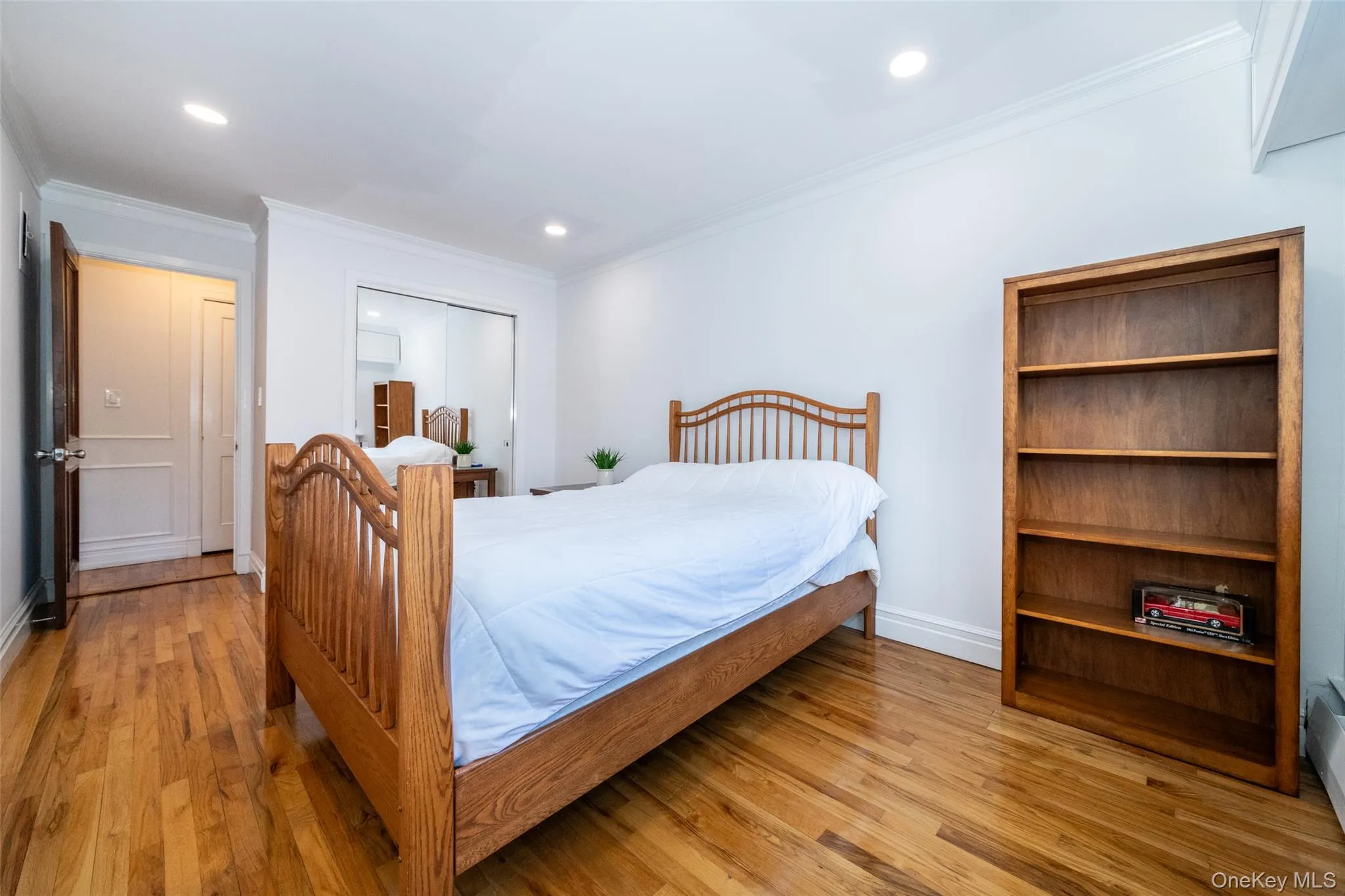 Bedroom featuring light wood finished floors, a closet, crown molding, and recessed lighting Bedroom featuring light wood finished floors, a closet, crown molding, and recessed lighting