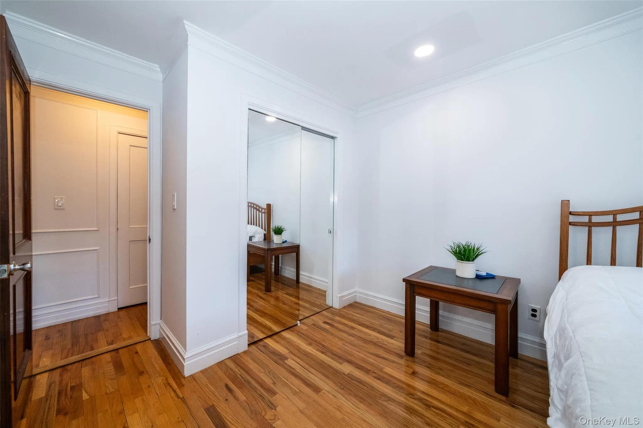 Bedroom with ornamental molding, a closet, and light wood-style floors Bedroom with ornamental molding, a closet, and light wood-style floors