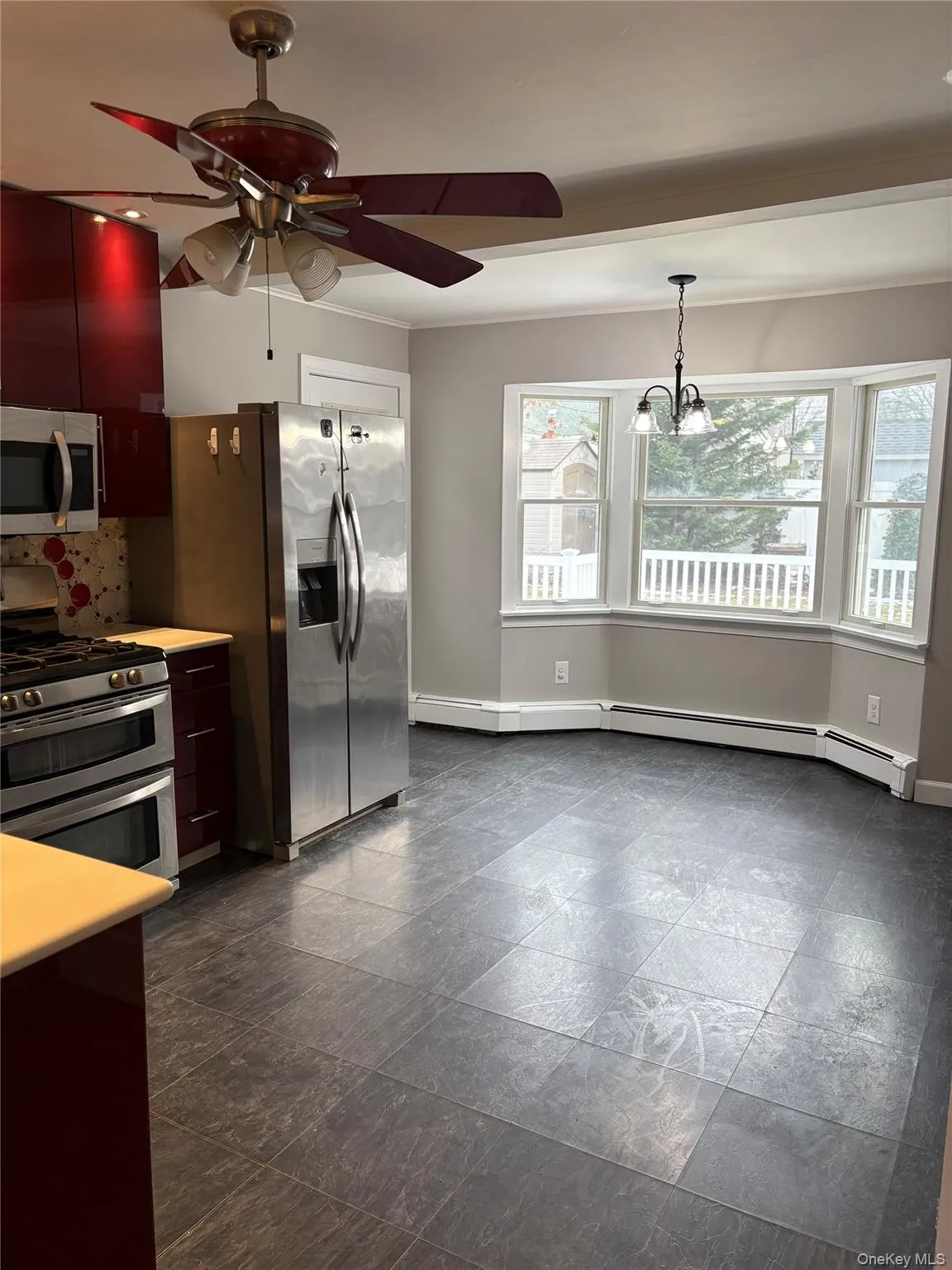 Kitchen with appliances with stainless steel finishes, light countertops, a ceiling fan, baseboard heating, and hanging light fixtures Kitchen with appliances with stainless steel finishes, light countertops, a ceiling fan, baseboard heating, and hanging light fixtures