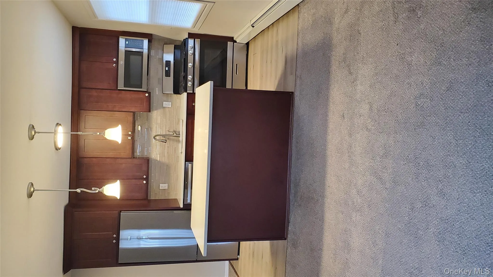 Kitchen with range, stainless steel refrigerator, baseboard heating, and light countertops Kitchen with range, stainless steel refrigerator, baseboard heating, and light countertops