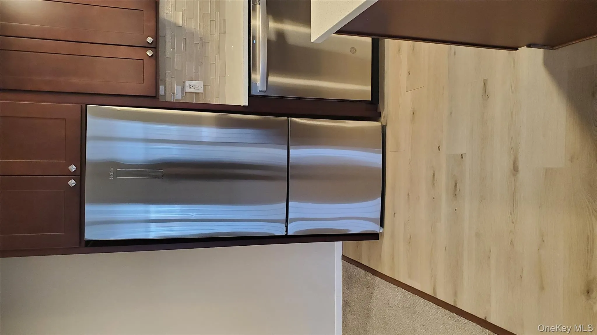 Kitchen with stainless steel fridge, dishwasher, dark brown cabinetry, tasteful backsplash, and light stone counters Kitchen with stainless steel fridge, dishwasher, dark brown cabinetry, tasteful backsplash, and light stone counters