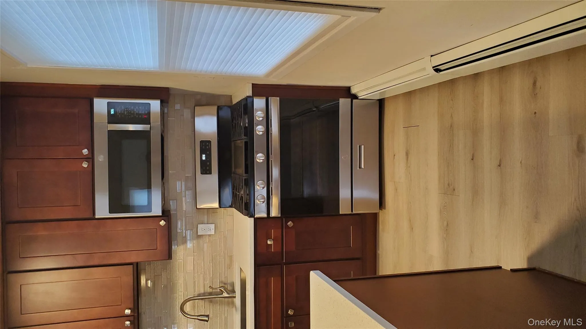 Kitchen featuring gas range, a baseboard heating unit, light wood finished floors, light stone counters, and tasteful backsplash Kitchen featuring gas range, a baseboard heating unit, light wood finished floors, light stone counters, and tasteful backsplash