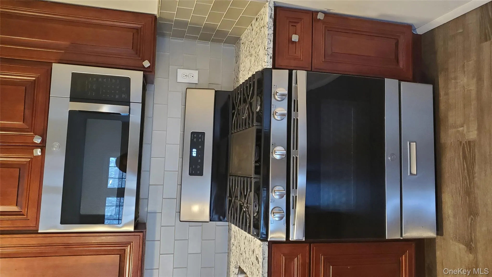 Kitchen with gas stove, light stone counters, wood finished floors, and tasteful backsplash Kitchen with gas stove, light stone counters, wood finished floors, and tasteful backsplash