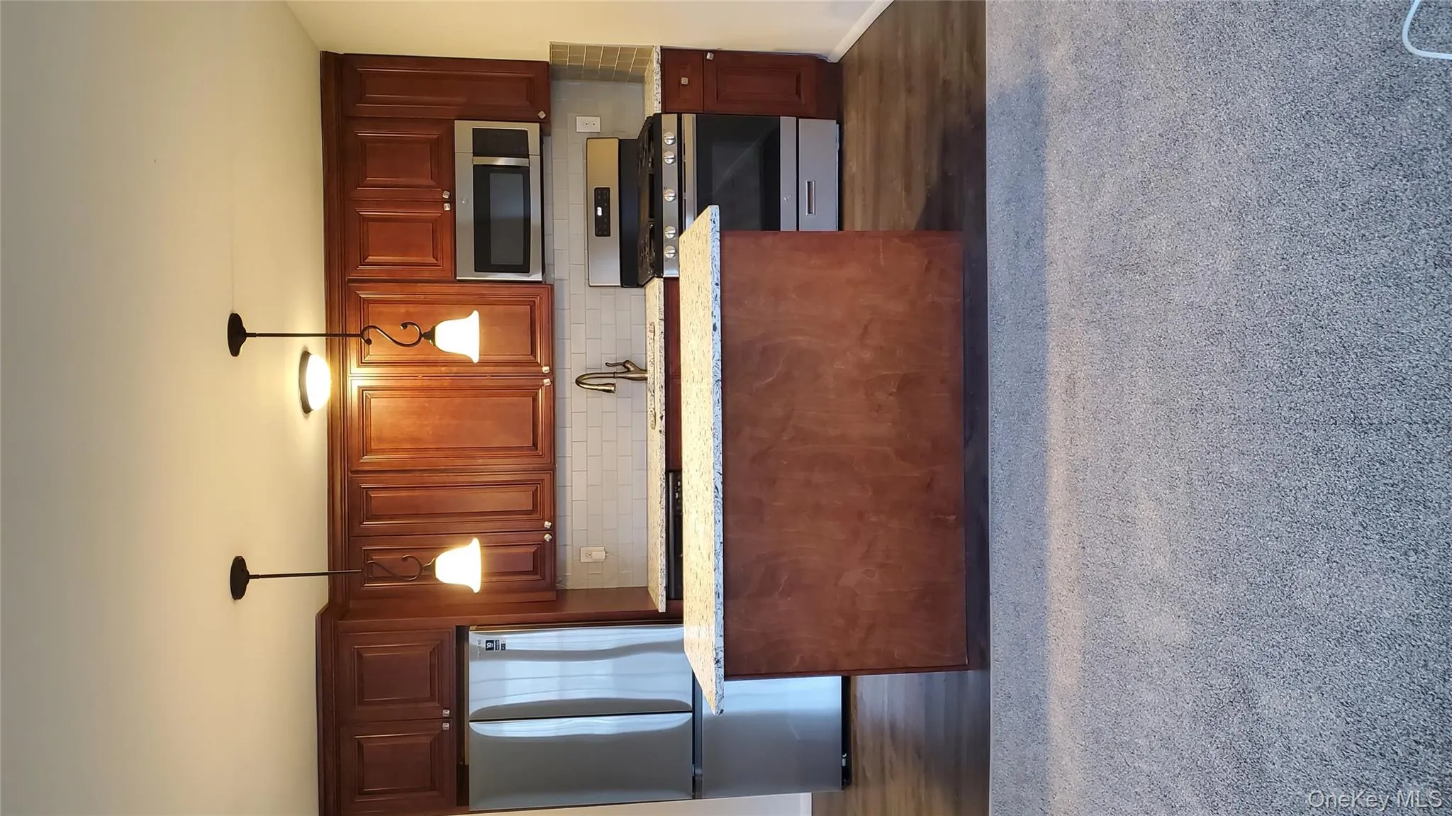 Kitchen with stainless steel fridge, stove, light stone countertops, and decorative backsplash Kitchen with stainless steel fridge, stove, light stone countertops, and decorative backsplash