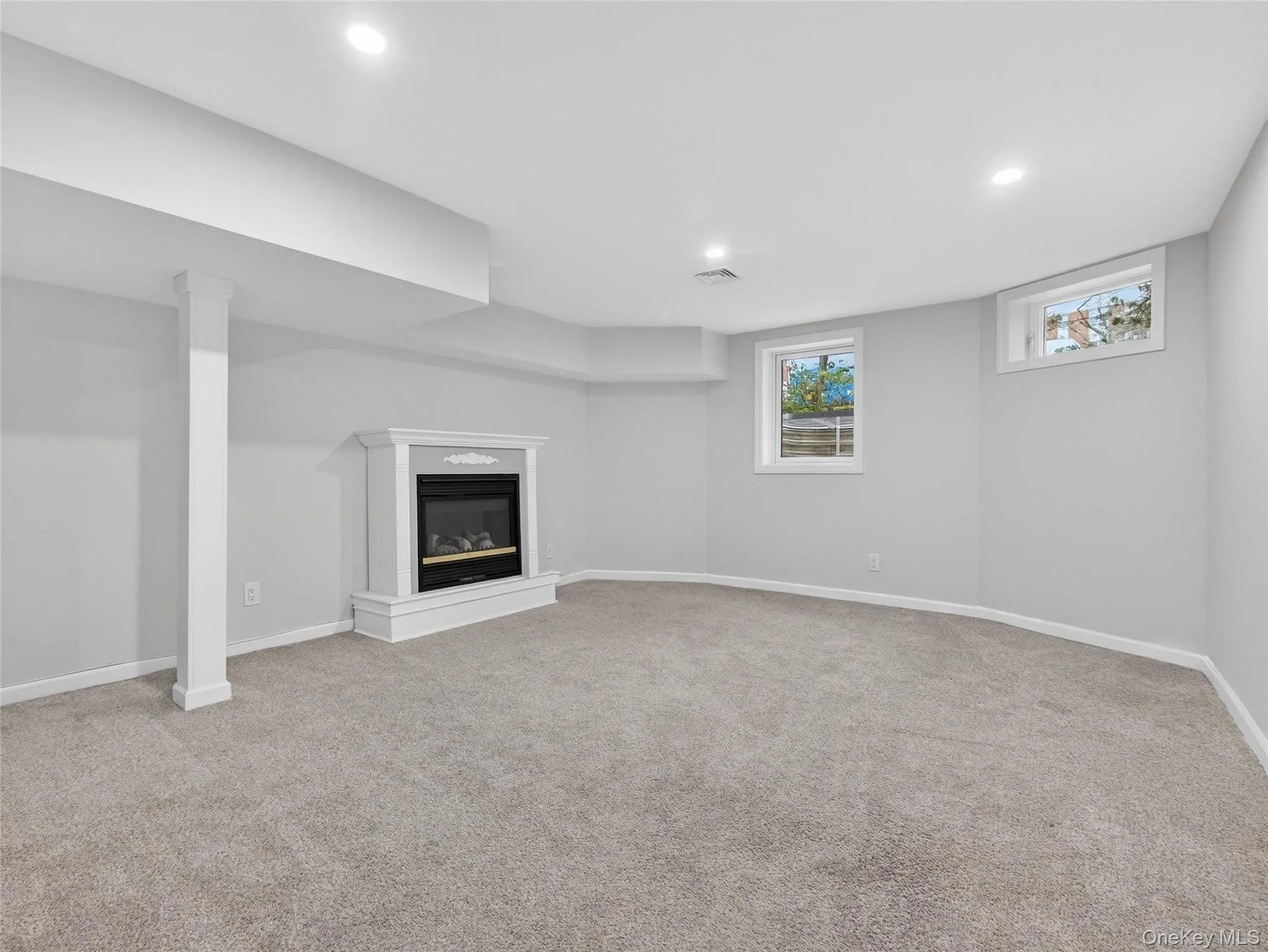 Below grade area featuring a glass covered fireplace, light carpet, and recessed lighting Below grade area featuring a glass covered fireplace, light carpet, and recessed lighting