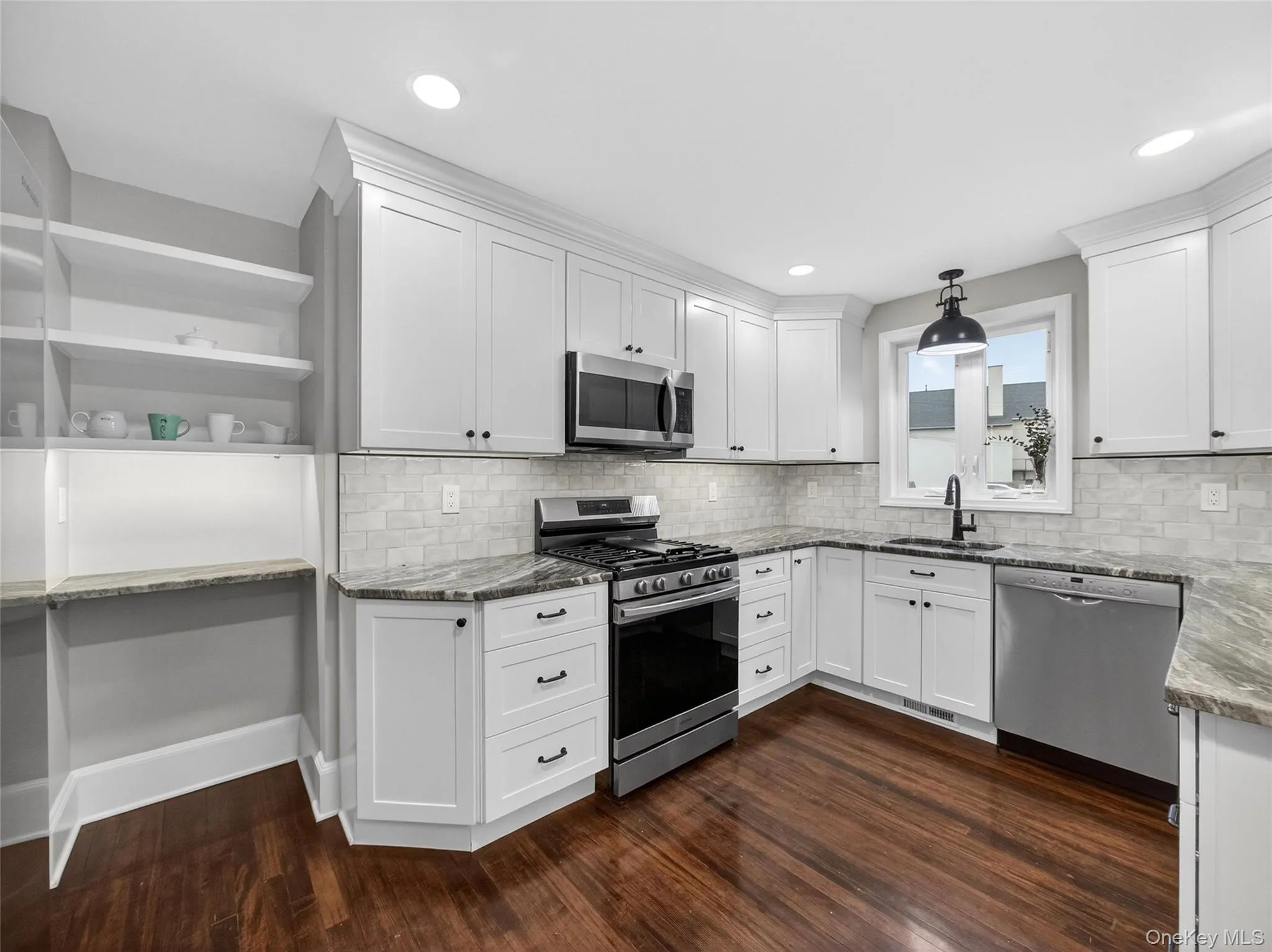 Kitchen featuring stainless steel appliances, light stone counters, white cabinets, and dark wood-type flooring Kitchen featuring stainless steel appliances, light stone counters, white cabinets, and dark wood-type flooring