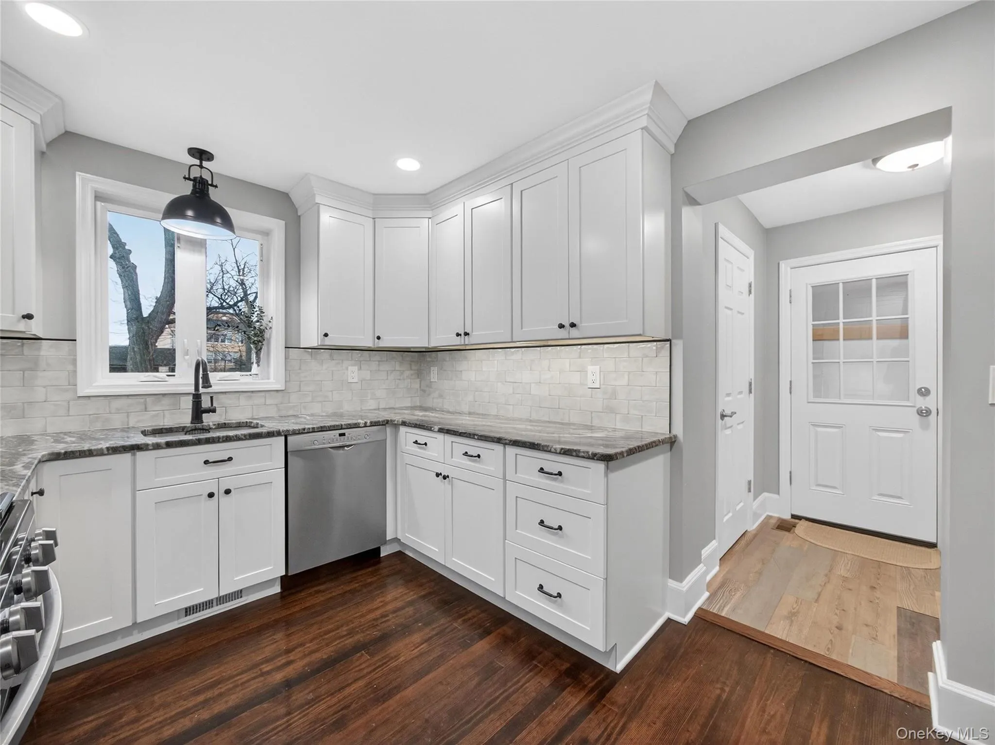 Kitchen featuring white cabinetry, appliances with stainless steel finishes, and dark stone countertops Kitchen featuring white cabinetry, appliances with stainless steel finishes, and dark stone countertops