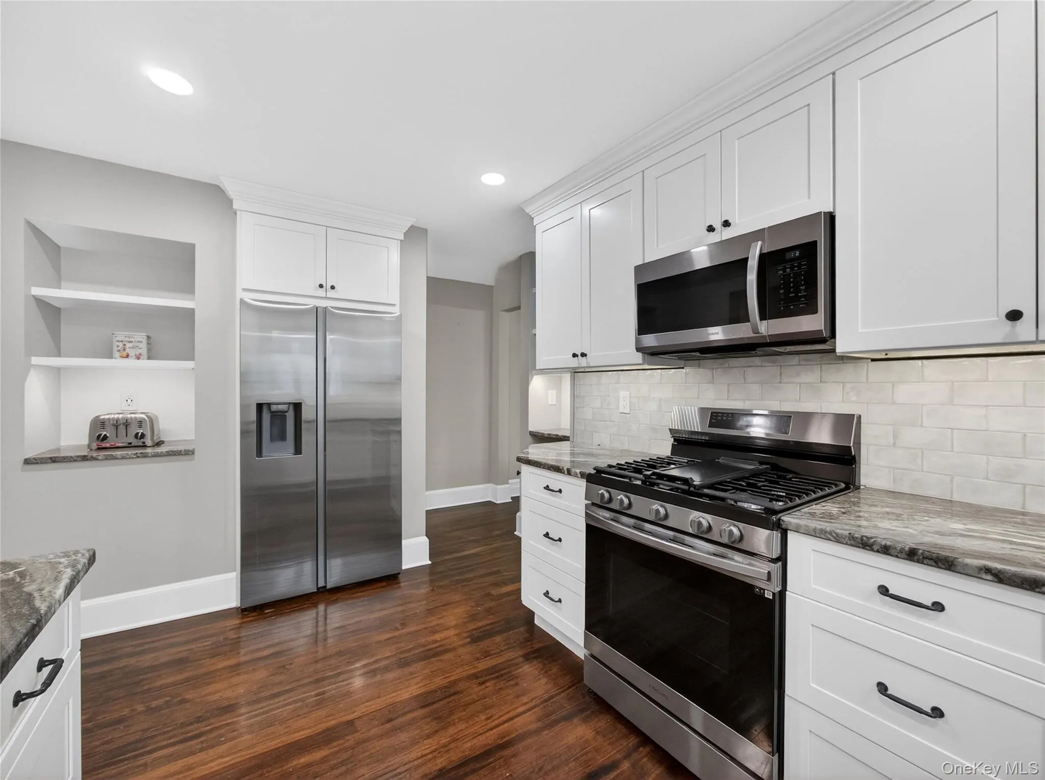 Kitchen with stainless steel appliances, dark stone countertops, white cabinets, built in features, and recessed lighting Kitchen with stainless steel appliances, dark stone countertops, white cabinets, built in features, and recessed lighting