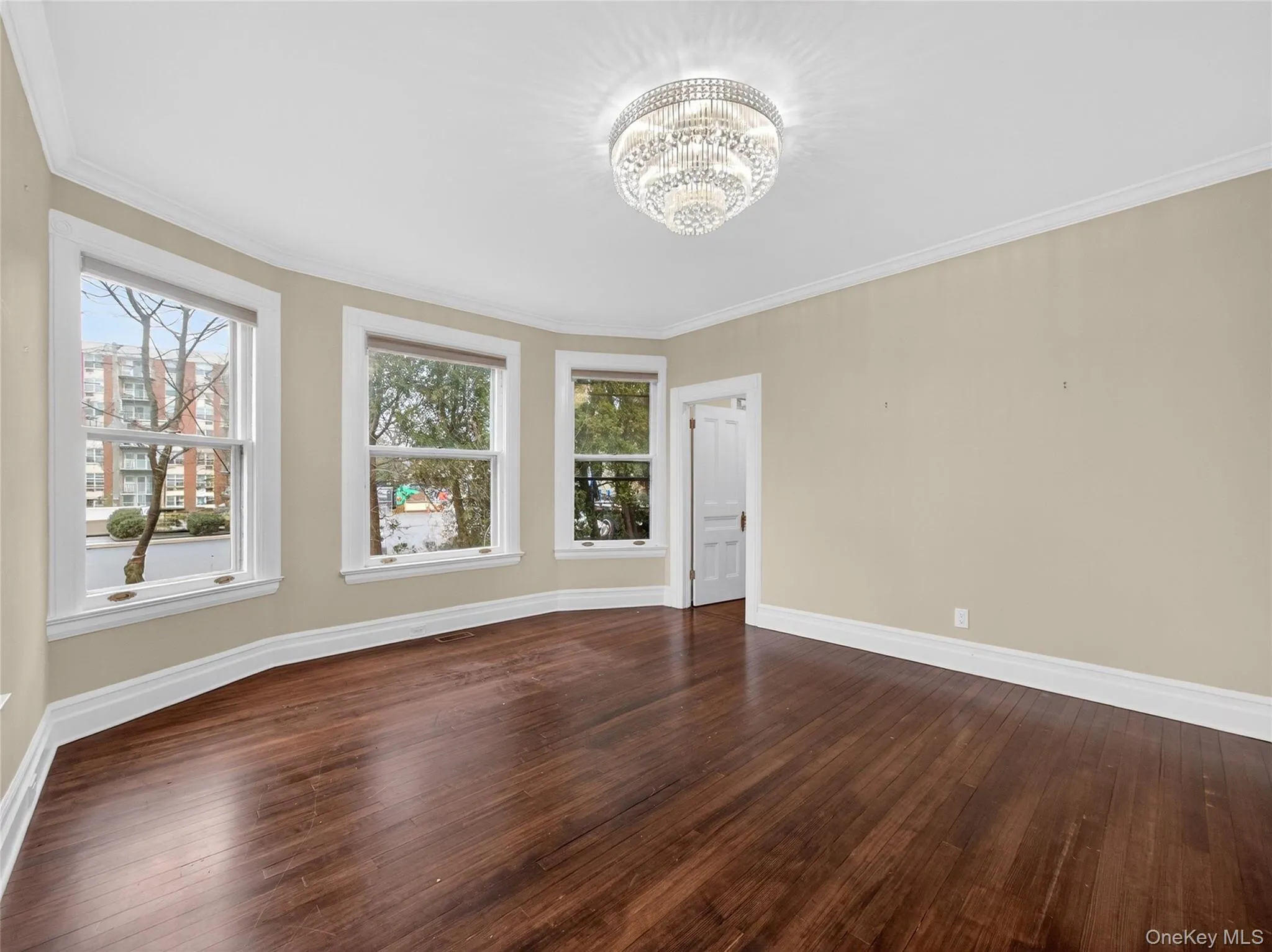 Spare room featuring crown molding, dark wood finished floors, and a chandelier Spare room featuring crown molding, dark wood finished floors, and a chandelier