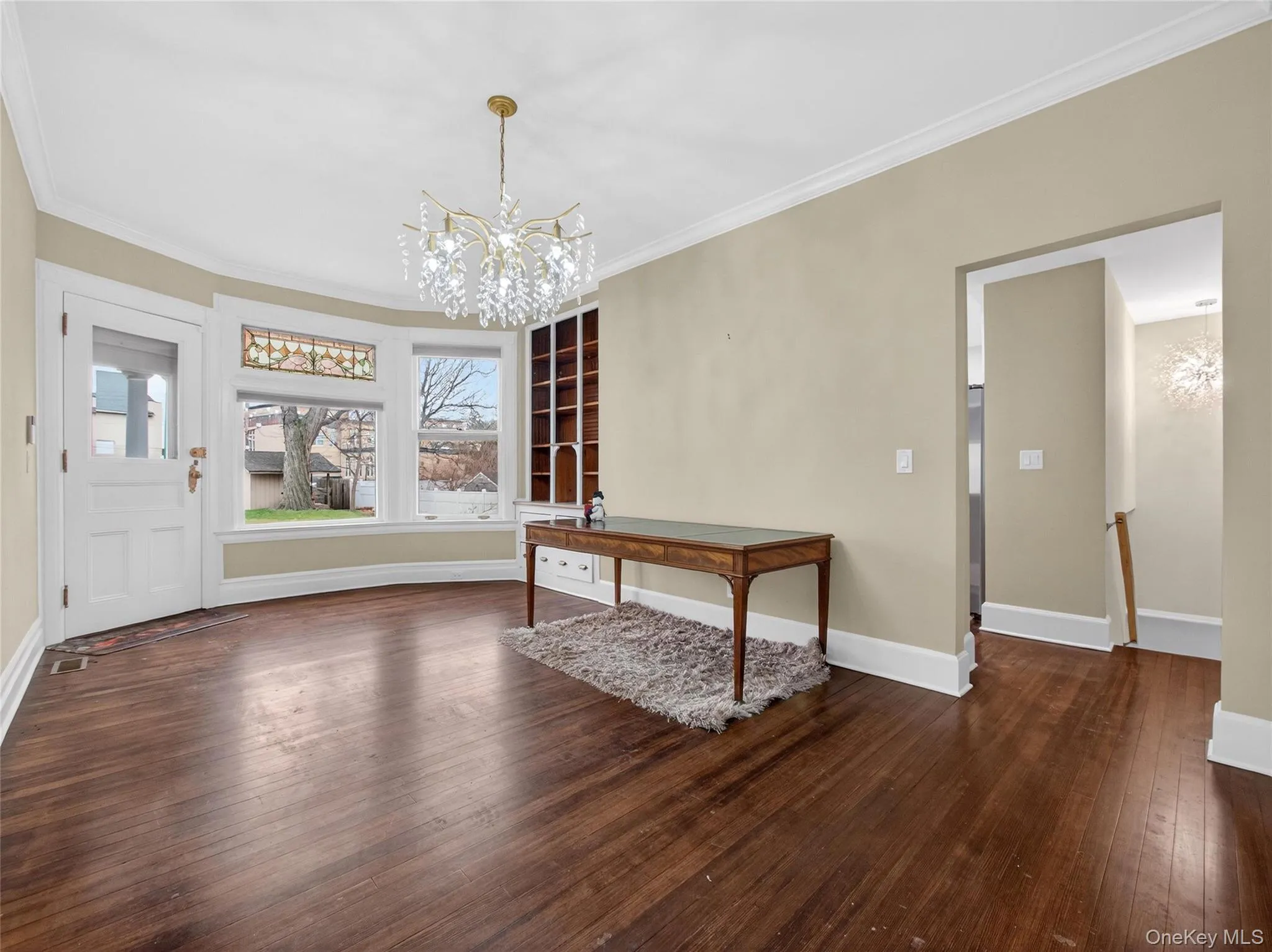 Unfurnished dining area featuring a chandelier, dark wood-style flooring, ornamental molding, and a desk Unfurnished dining area featuring a chandelier, dark wood-style flooring, ornamental molding, and a desk