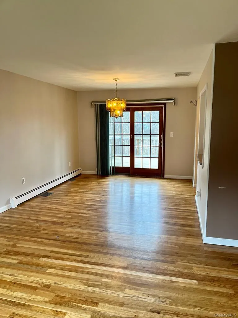 Spare room with a chandelier, a baseboard radiator, and light wood-style flooring Spare room with a chandelier, a baseboard radiator, and light wood-style flooring