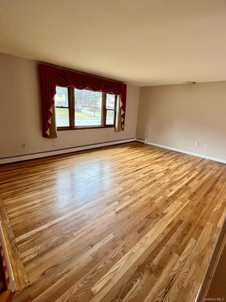 Empty room with a baseboard heating unit and light wood-style floors Empty room with a baseboard heating unit and light wood-style floors