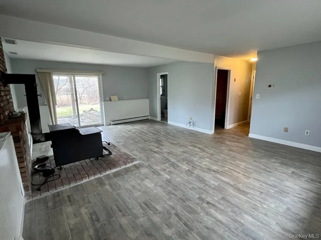 Living area featuring wood finished floors and a baseboard heating unit Living area featuring wood finished floors and a baseboard heating unit