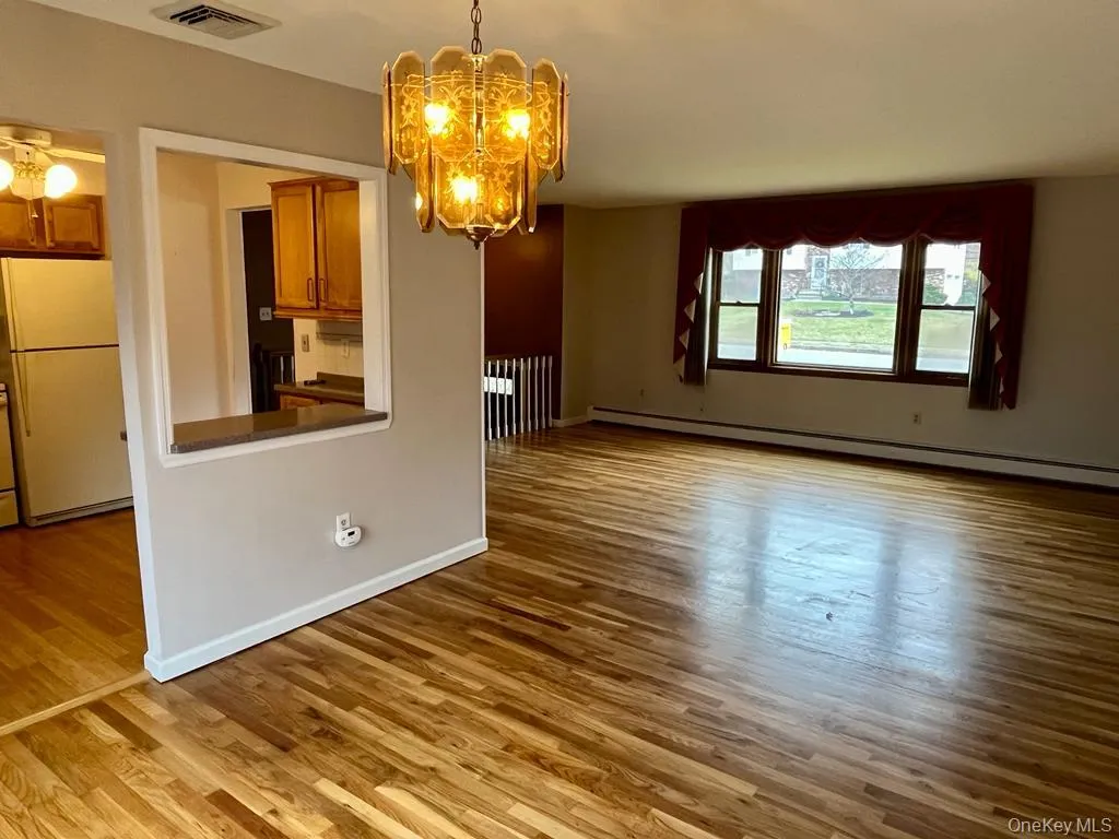 Unfurnished dining area featuring light wood finished floors, a chandelier, and a baseboard radiator Unfurnished dining area featuring light wood finished floors, a chandelier, and a baseboard radiator