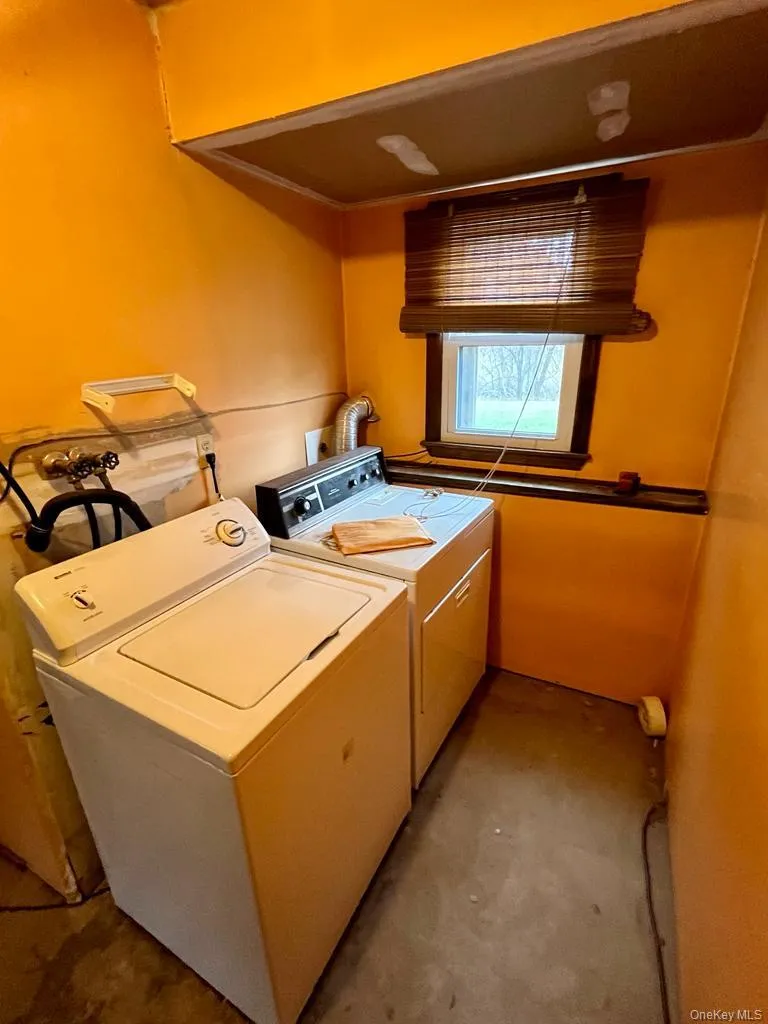 Laundry room with unfinished concrete flooring and washer and clothes dryer Laundry room with unfinished concrete flooring and washer and clothes dryer