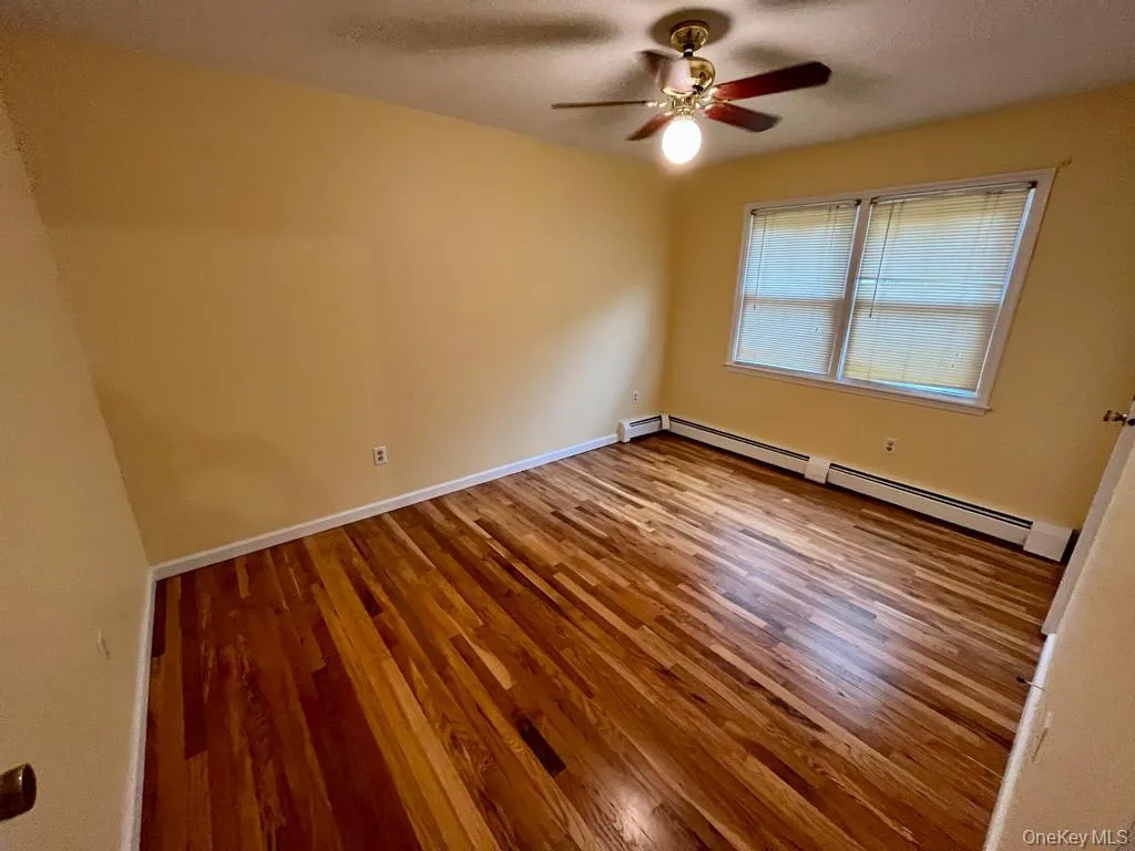 Unfurnished room featuring a baseboard heating unit, light wood-style flooring, a textured ceiling, and a ceiling fan Unfurnished room featuring a baseboard heating unit, light wood-style flooring, a textured ceiling, and a ceiling fan