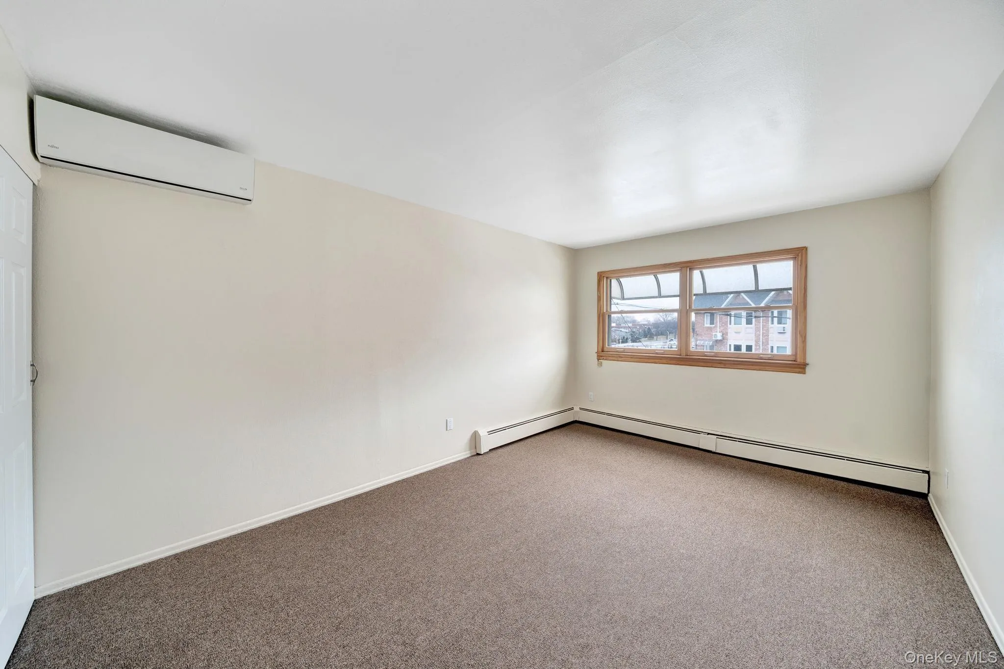 Carpeted spare room featuring a wall unit AC and a baseboard radiator Carpeted spare room featuring a wall unit AC and a baseboard radiator