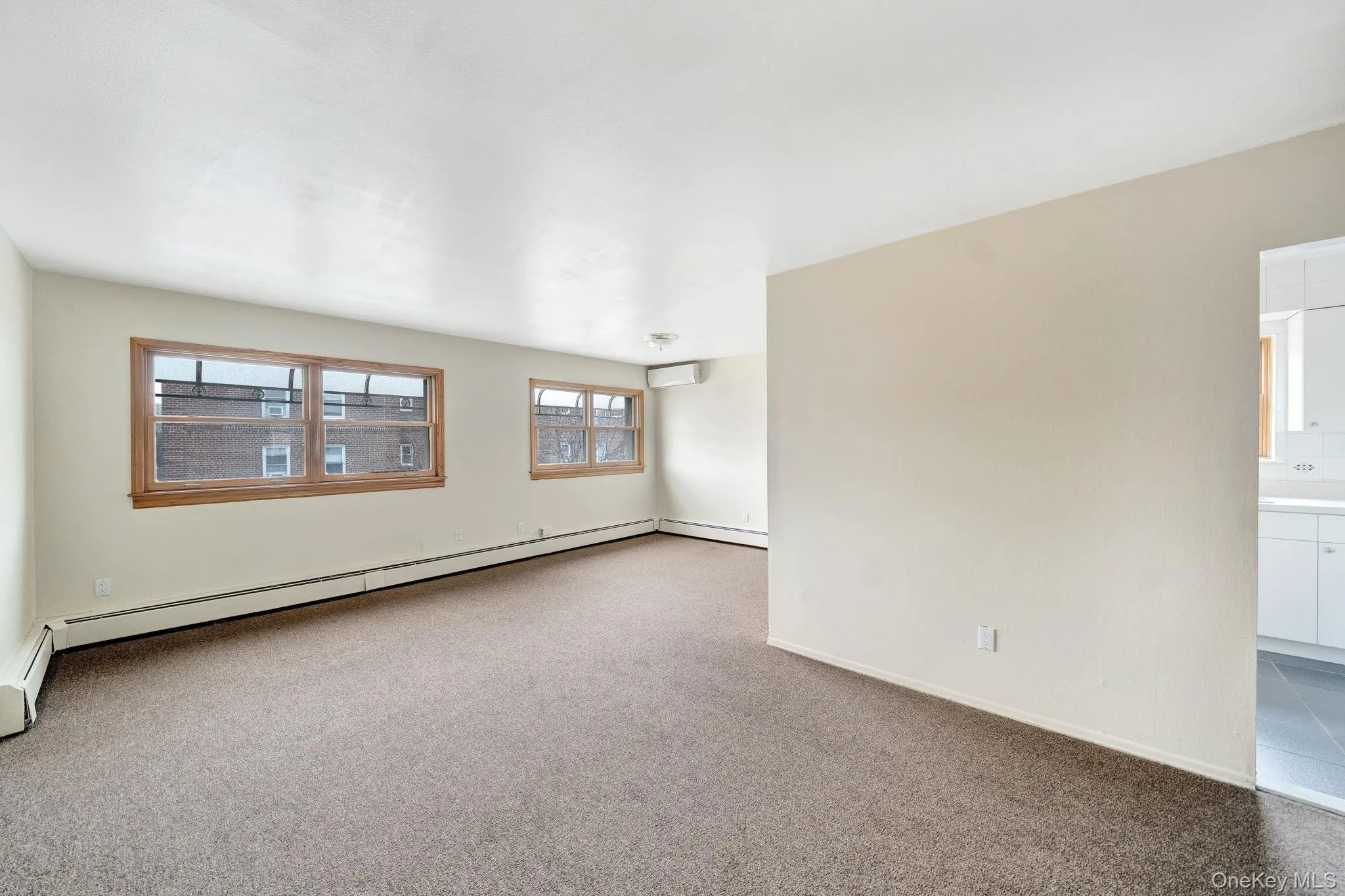 Carpeted empty room with a baseboard radiator and a wall mounted air conditioner Carpeted empty room with a baseboard radiator and a wall mounted air conditioner