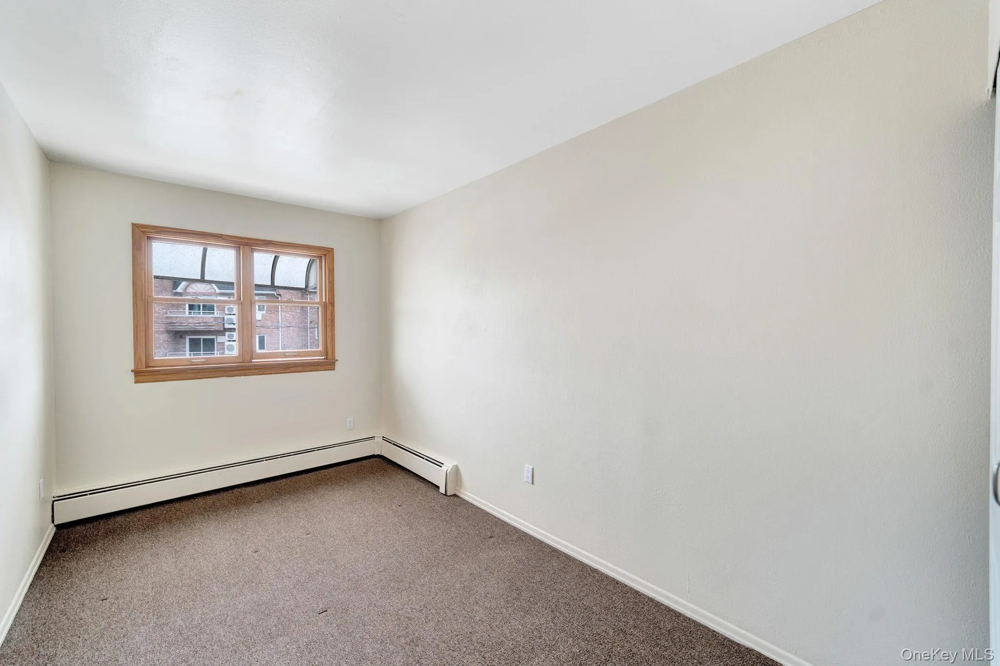 Carpeted spare room featuring baseboards and a baseboard heating unit Carpeted spare room featuring baseboards and a baseboard heating unit