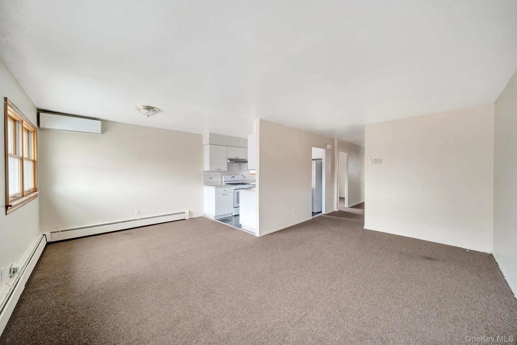 Spare room featuring dark carpet, a baseboard heating unit, and a wall mounted AC Spare room featuring dark carpet, a baseboard heating unit, and a wall mounted AC