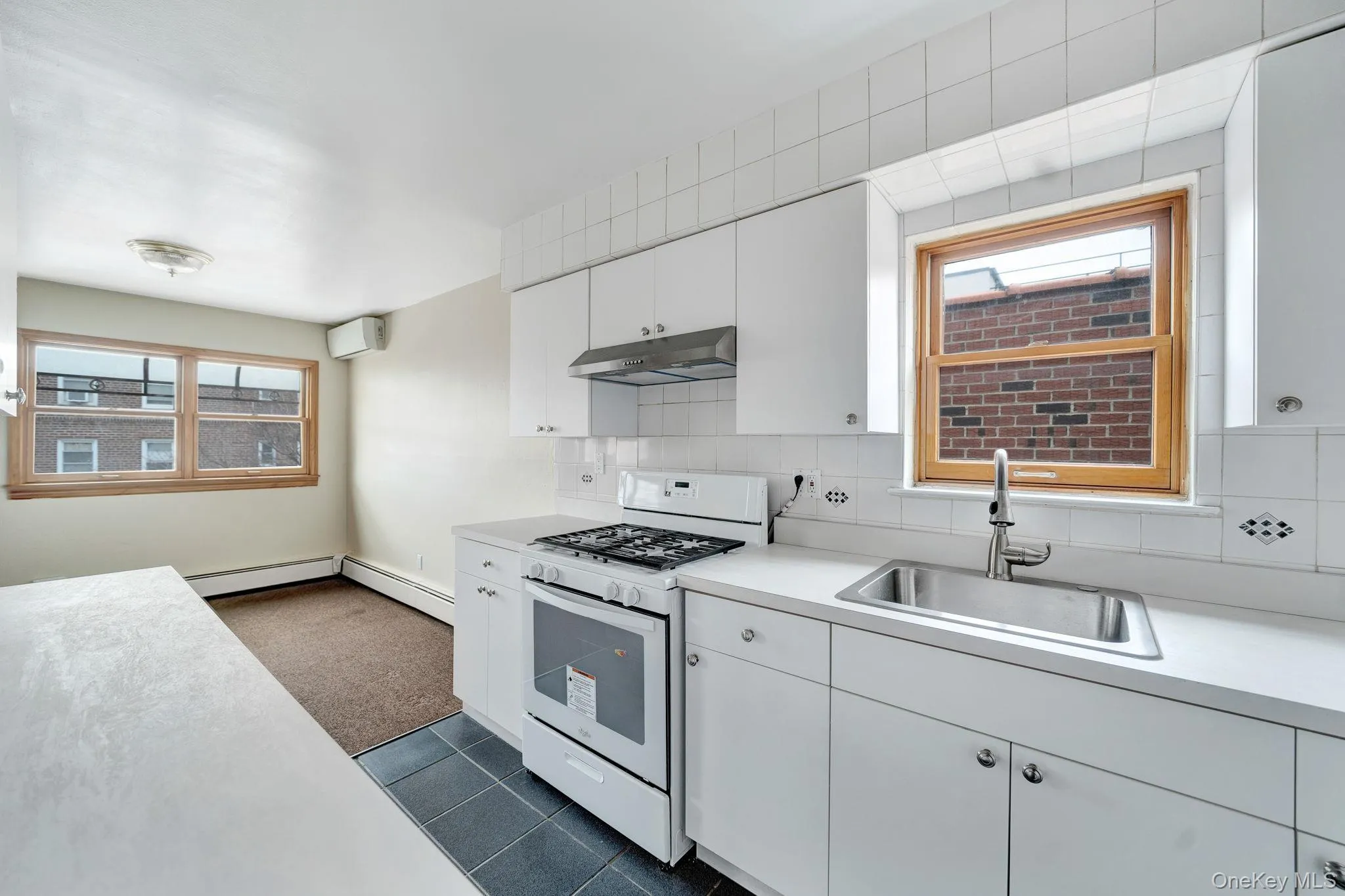 Kitchen with white gas range, light countertops, white cabinets, and decorative backsplash Kitchen with white gas range, light countertops, white cabinets, and decorative backsplash