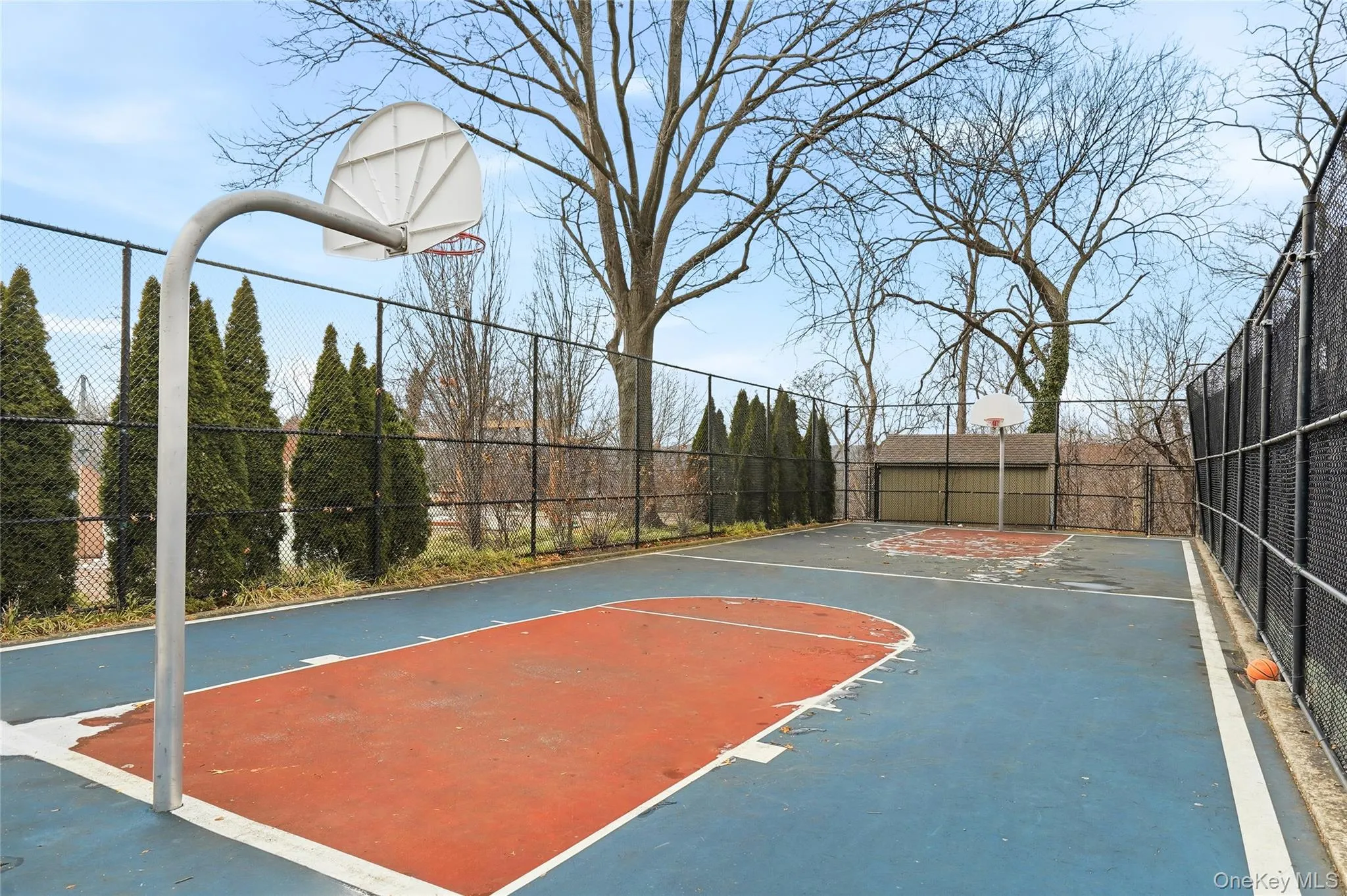 View of sport court featuring basketball court and a patio area View of sport court featuring basketball court and a patio area