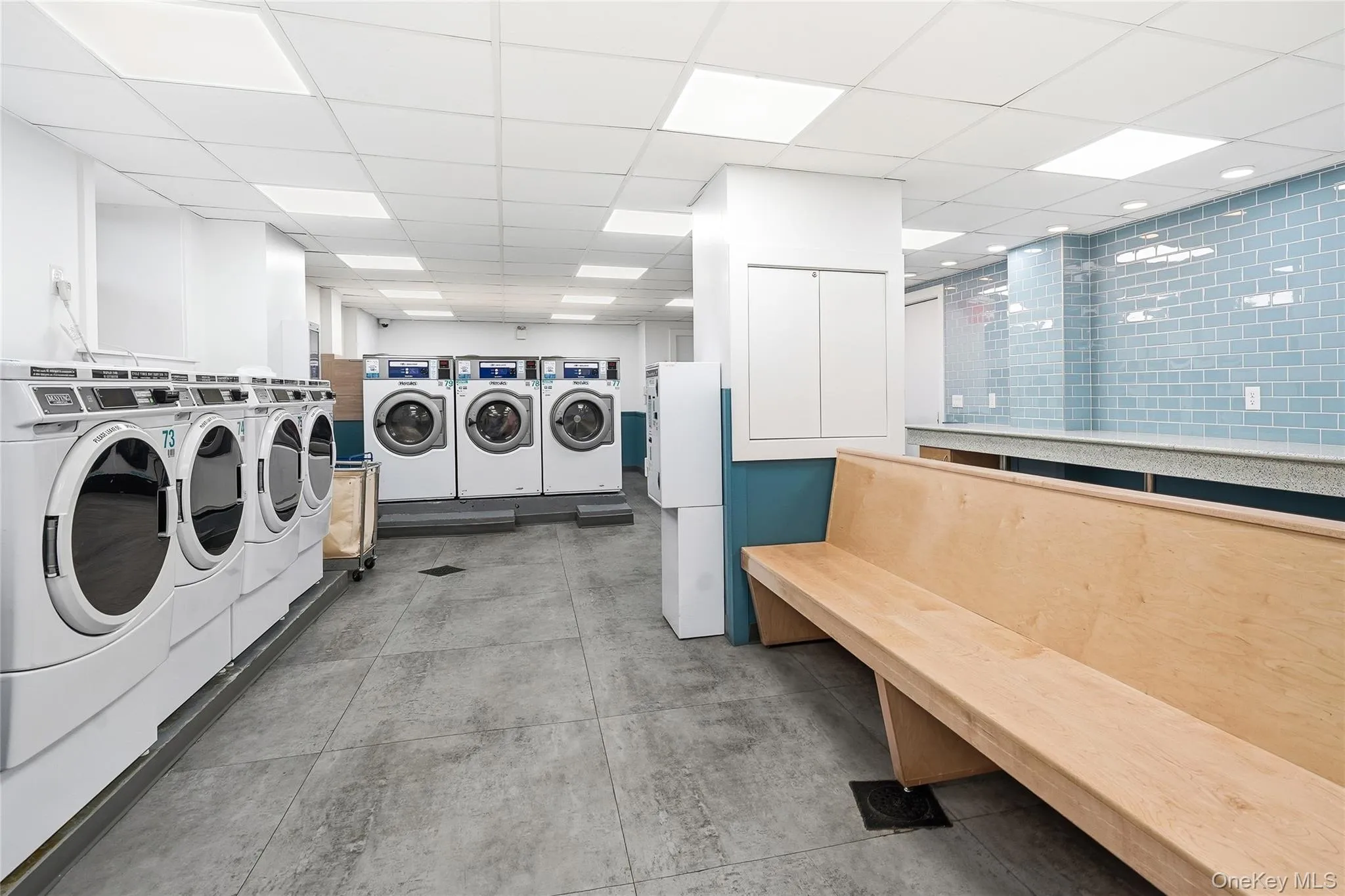 Community laundry with washing machine and dryer and a paneled ceiling Community laundry with washing machine and dryer and a paneled ceiling