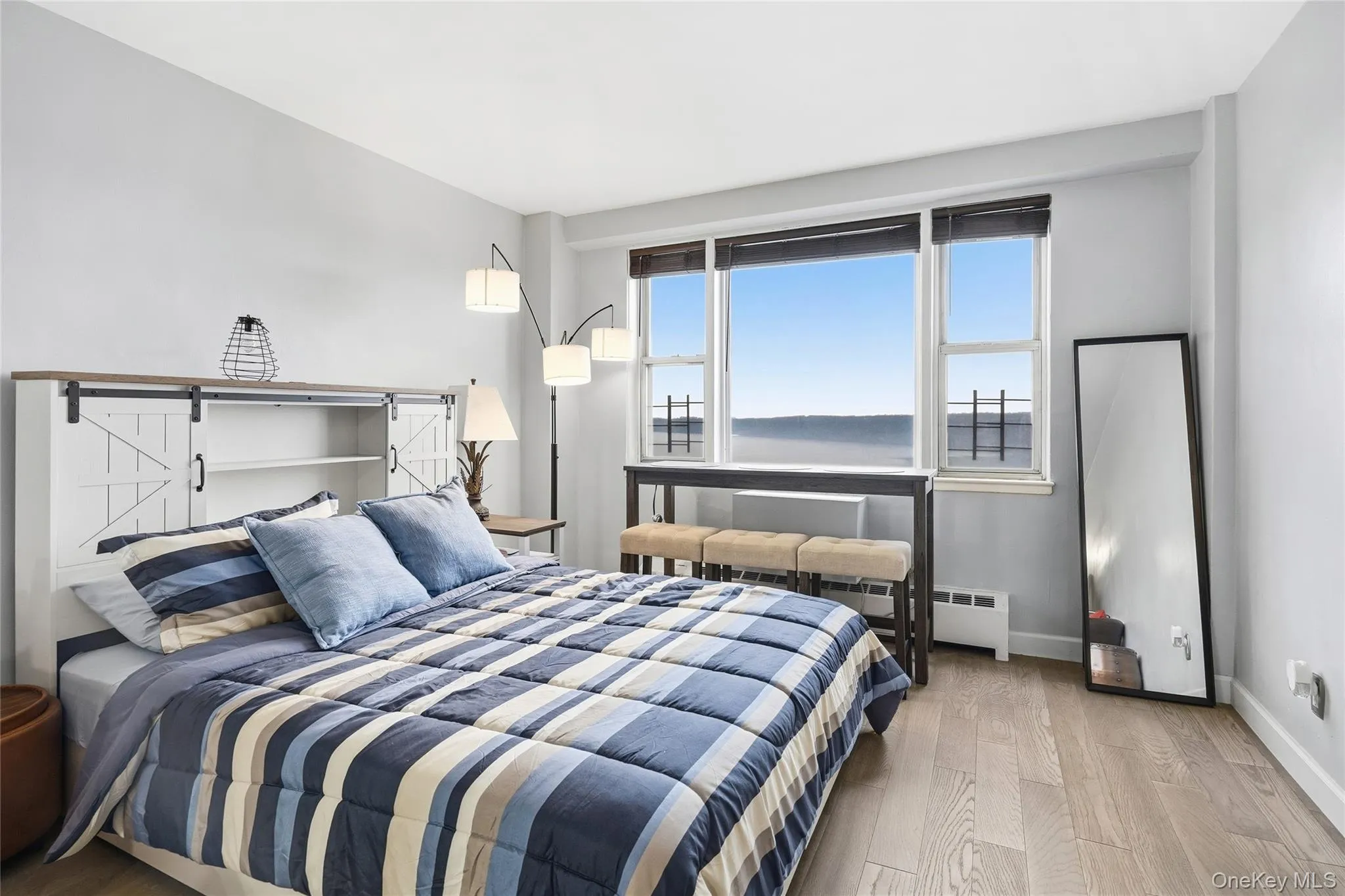Bedroom featuring wood finished floors and a baseboard heating unit Bedroom featuring wood finished floors and a baseboard heating unit