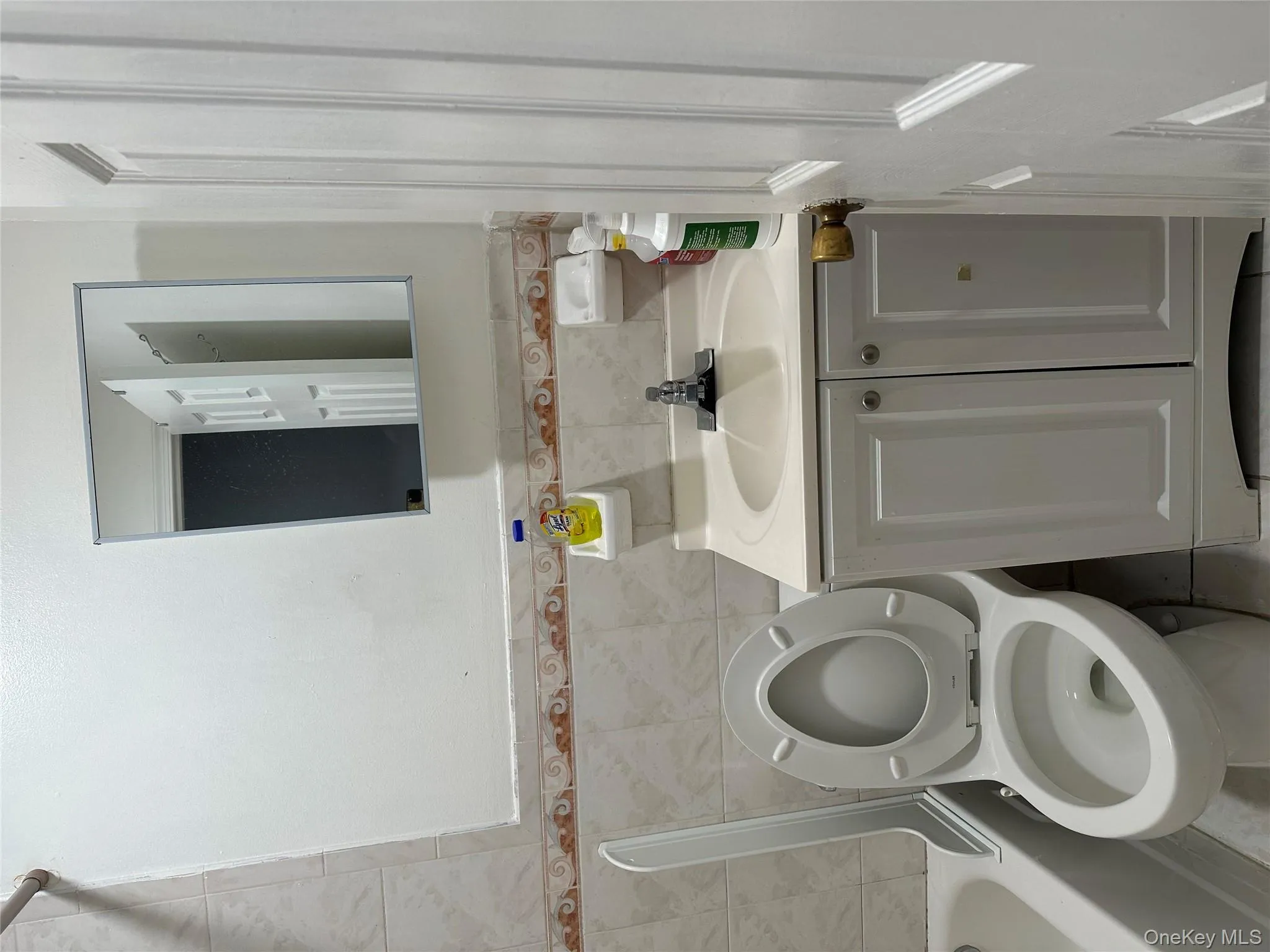 Full bath featuring tile walls, vanity, bathing tub / shower combination, and a wainscoted wall Full bath featuring tile walls, vanity, bathing tub / shower combination, and a wainscoted wall