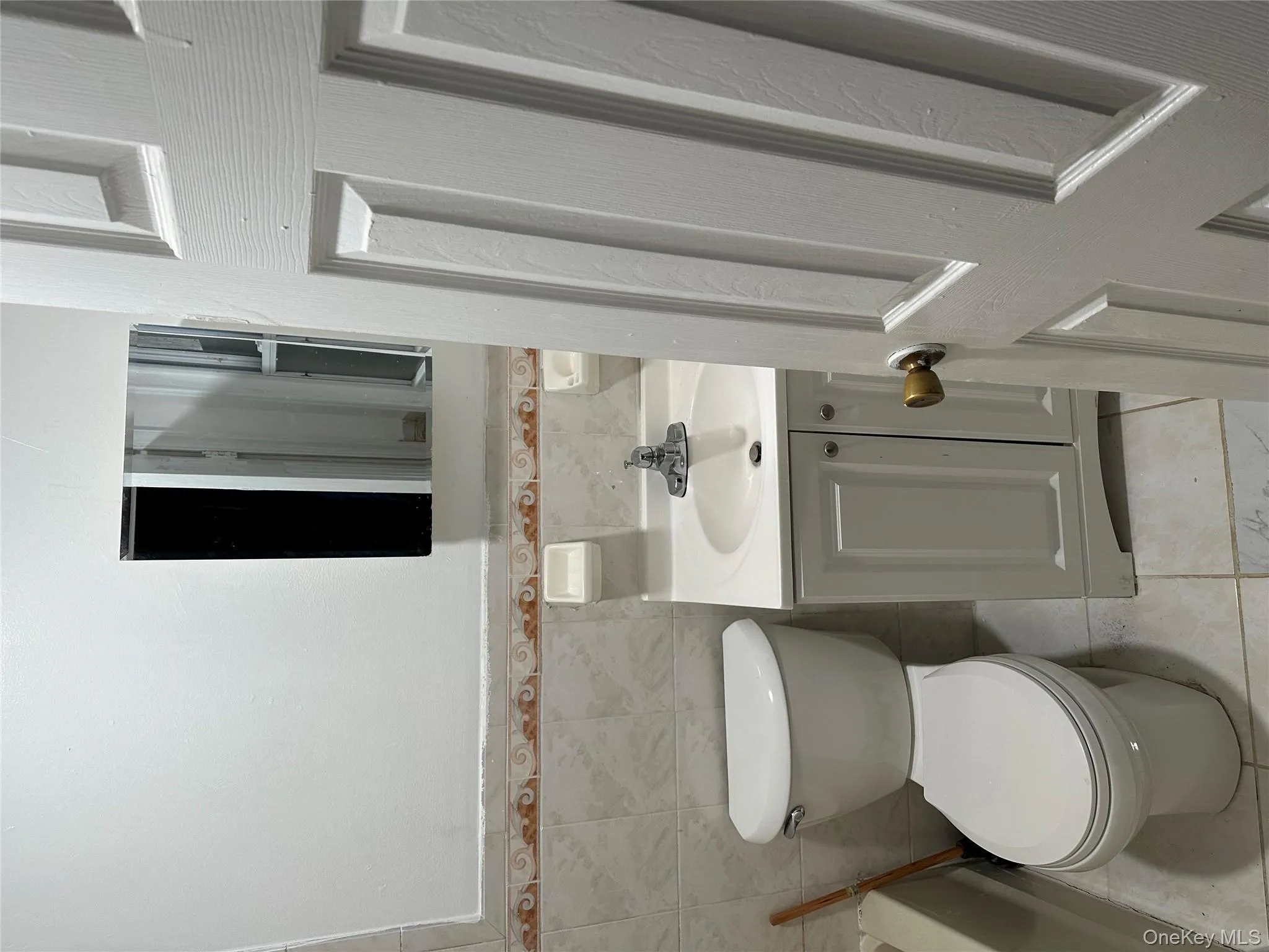 Full bath with vanity, a tub to relax in, tile walls, light tile patterned floors, and wainscoting Full bath with vanity, a tub to relax in, tile walls, light tile patterned floors, and wainscoting