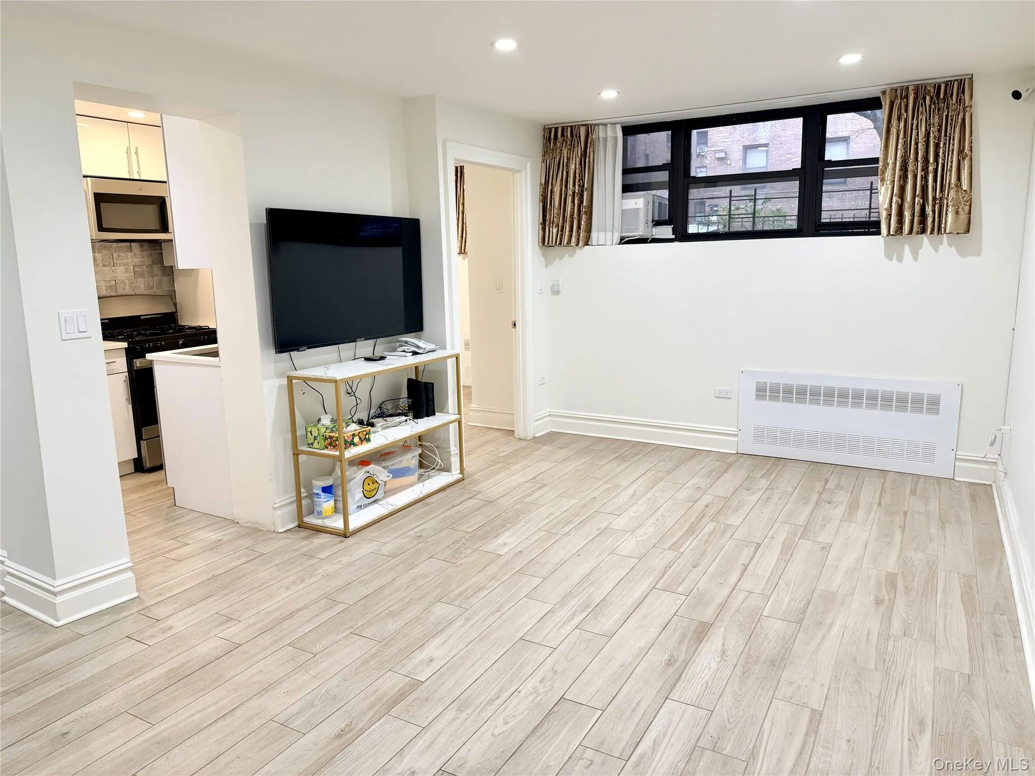 Unfurnished living room with recessed lighting, radiator heating unit, and light wood-style floors Unfurnished living room with recessed lighting, radiator heating unit, and light wood-style floors
