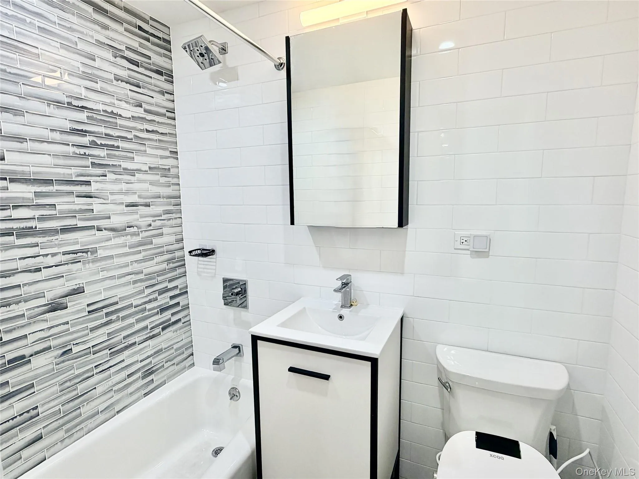 Full bathroom with vanity, shower / bath combination, and tile walls Full bathroom with vanity, shower / bath combination, and tile walls