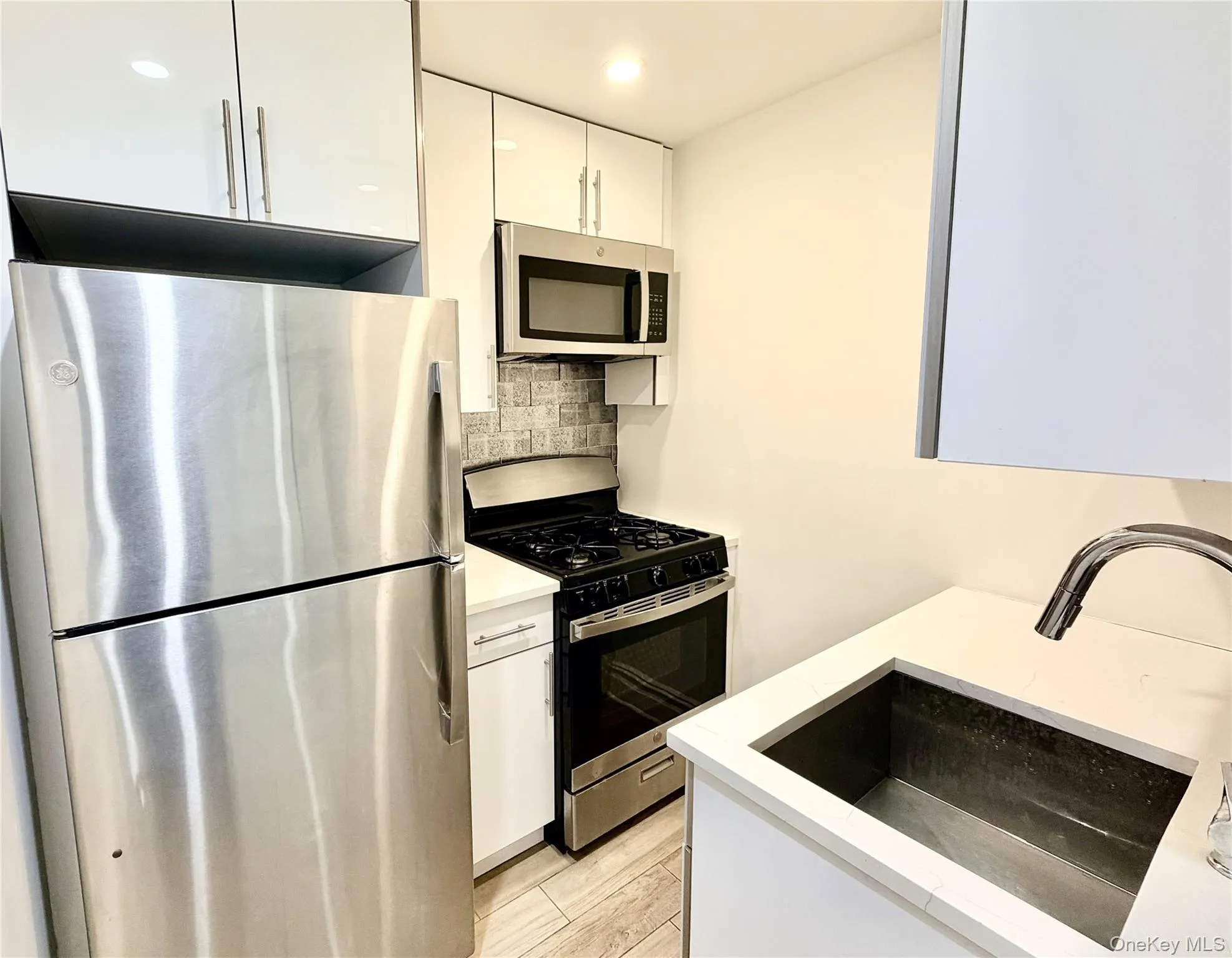 Kitchen featuring stainless steel appliances, white cabinets, tasteful backsplash, recessed lighting, and modern cabinets Kitchen featuring stainless steel appliances, white cabinets, tasteful backsplash, recessed lighting, and modern cabinets