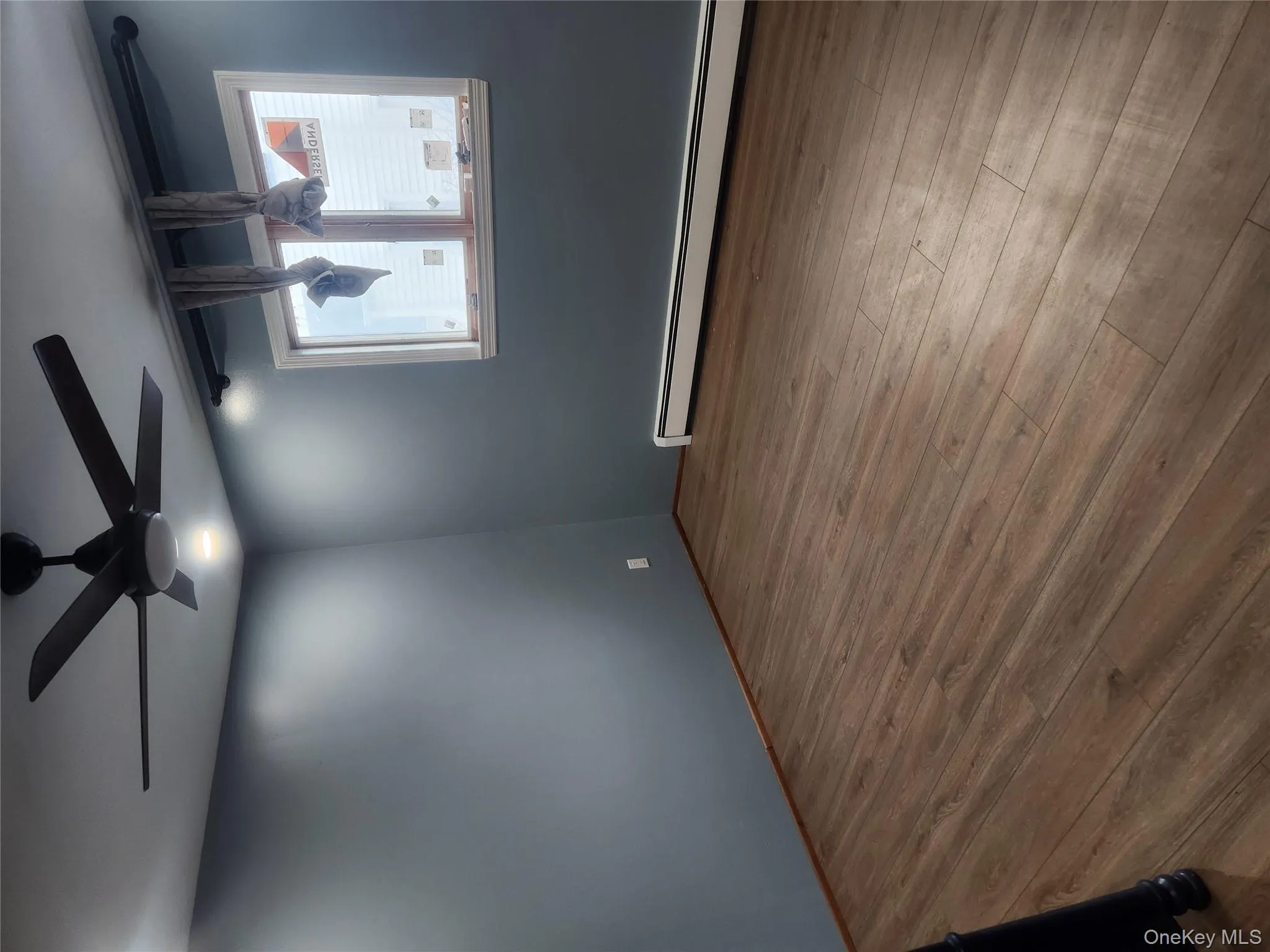 Empty room featuring a baseboard radiator, wood finished floors, and ceiling fan Empty room featuring a baseboard radiator, wood finished floors, and ceiling fan