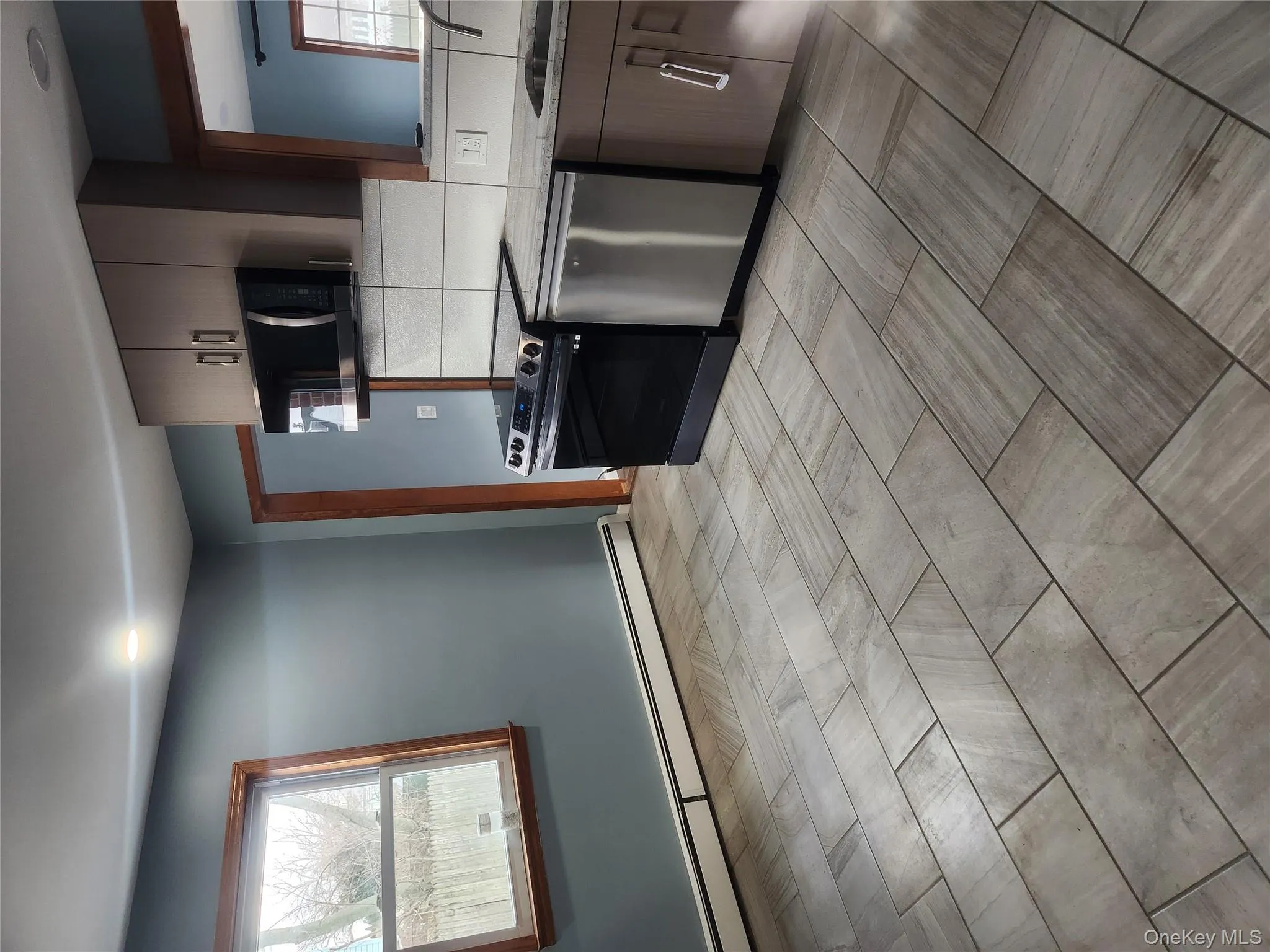 Kitchen featuring range, a baseboard heating unit, dishwashing machine, tasteful backsplash, and light stone counters Kitchen featuring range, a baseboard heating unit, dishwashing machine, tasteful backsplash, and light stone counters