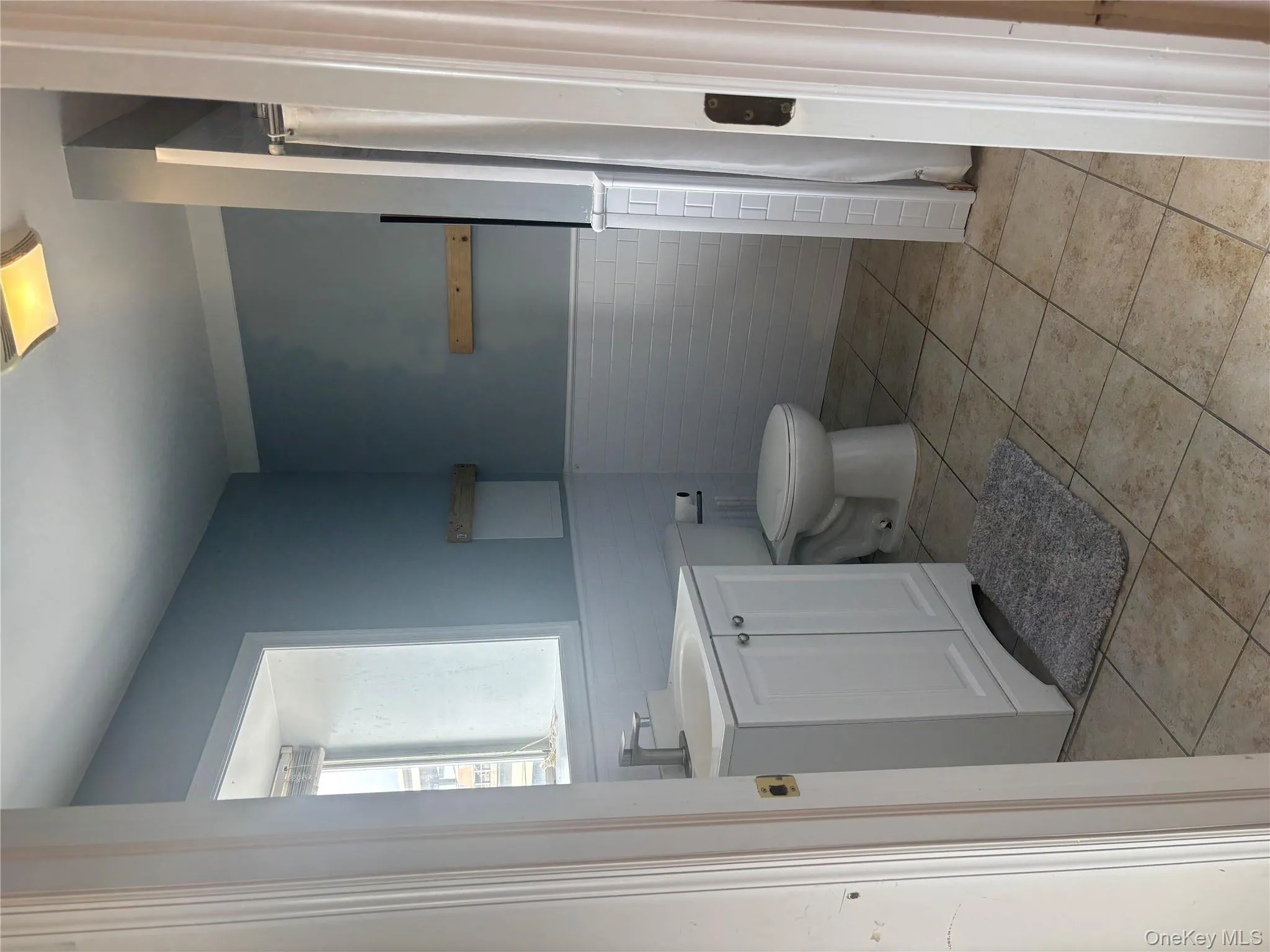Full bathroom with vanity, a wainscoted wall, curtained shower, light tile patterned floors, and tile walls Full bathroom with vanity, a wainscoted wall, curtained shower, light tile patterned floors, and tile walls