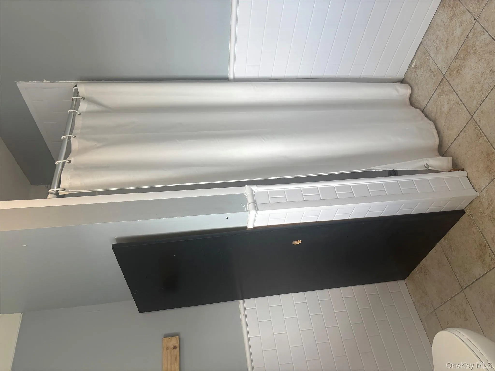 Full bathroom with a wainscoted wall, tile walls, a stall shower, and light tile patterned floors Full bathroom with a wainscoted wall, tile walls, a stall shower, and light tile patterned floors