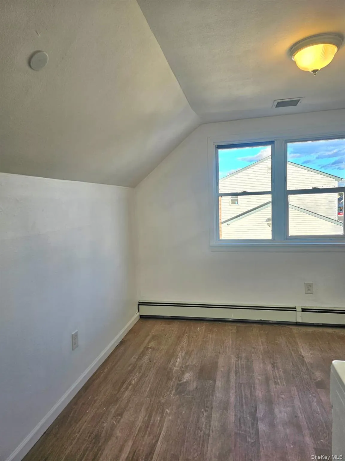 Additional living space with vaulted ceiling, dark wood finished floors, and baseboard heating Additional living space with vaulted ceiling, dark wood finished floors, and baseboard heating